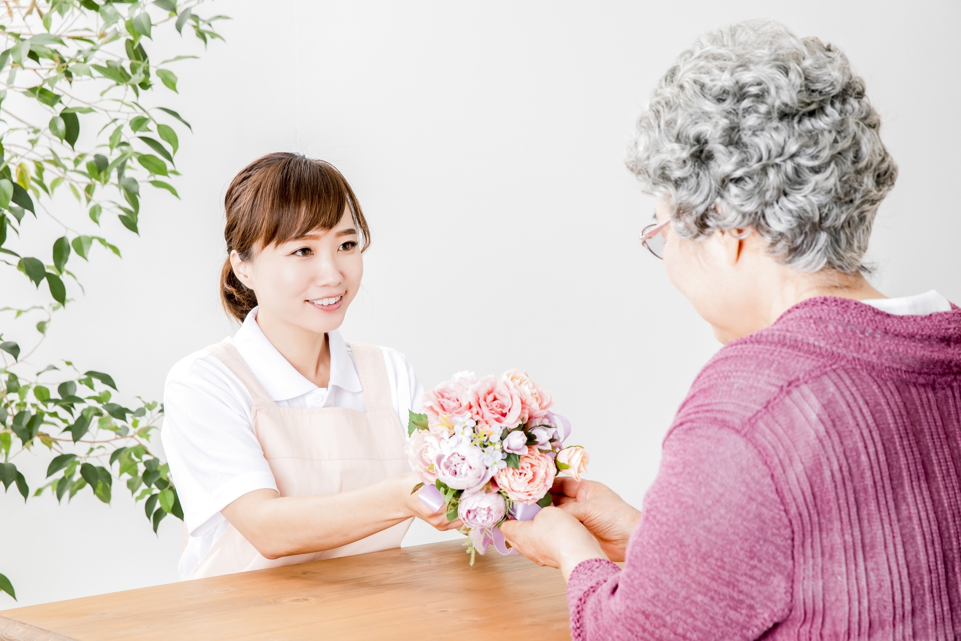 高齢者の女性と花束を持つ介護士