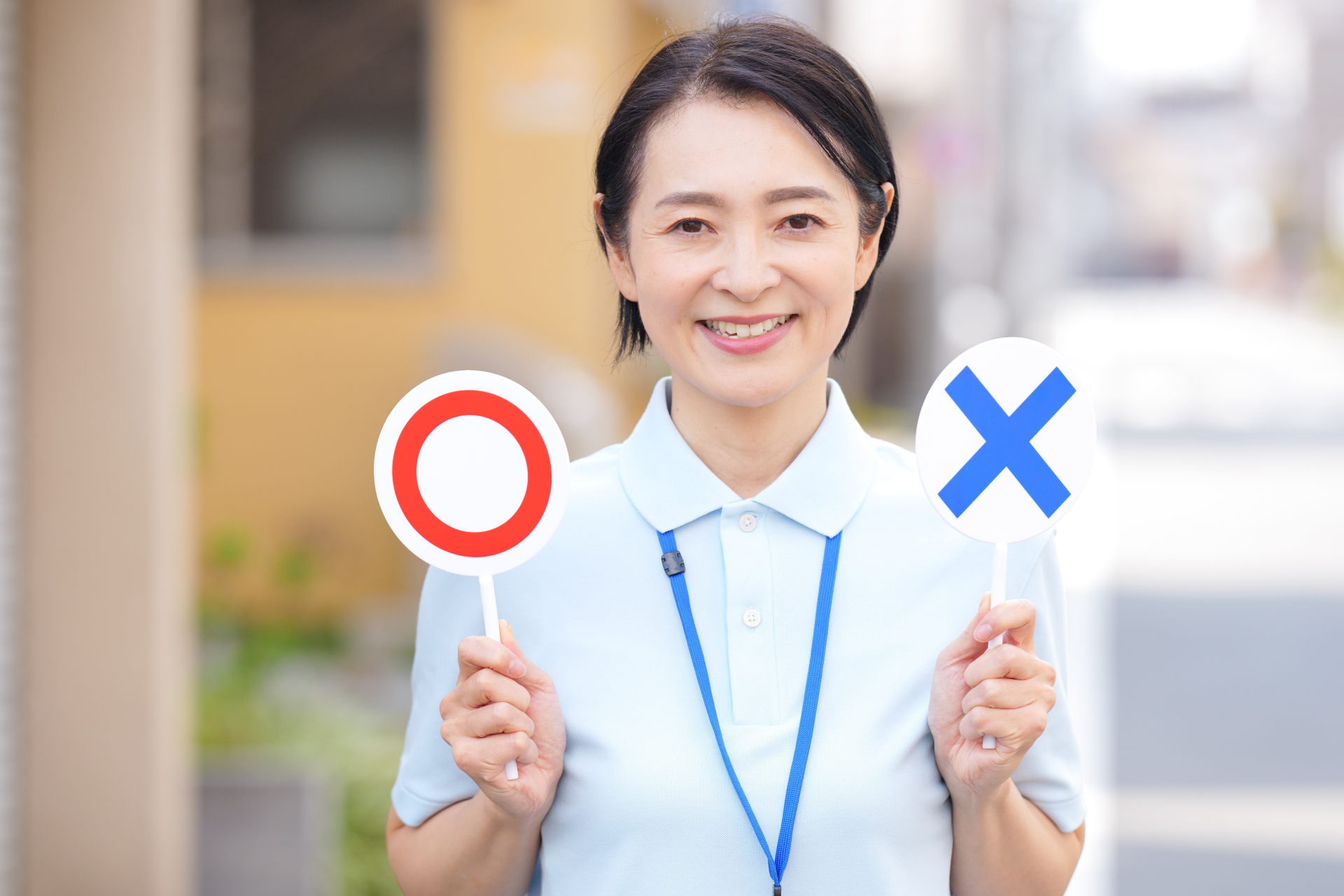 〇✕の札を持った女性