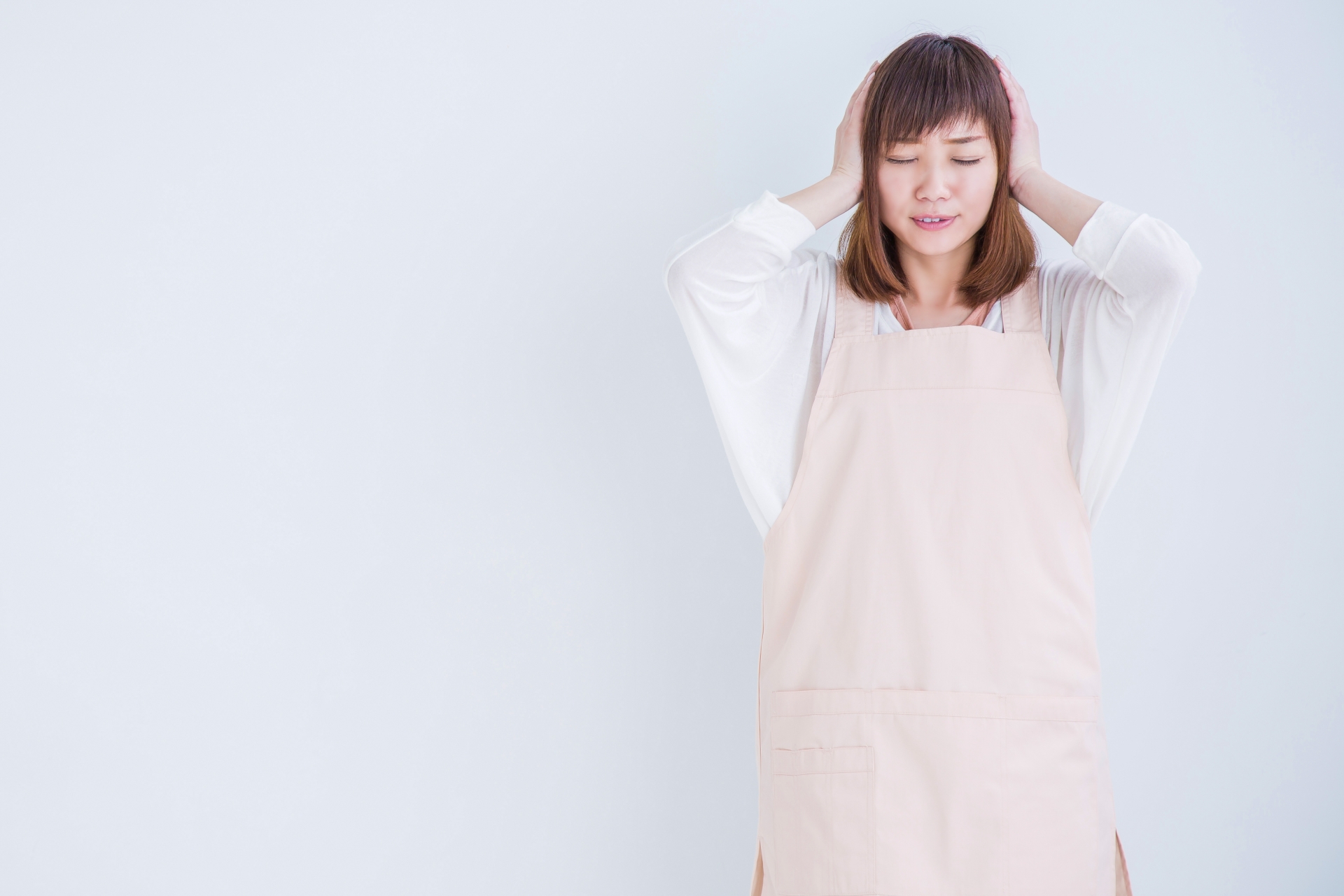 頭を抱えるエプロン姿の女性