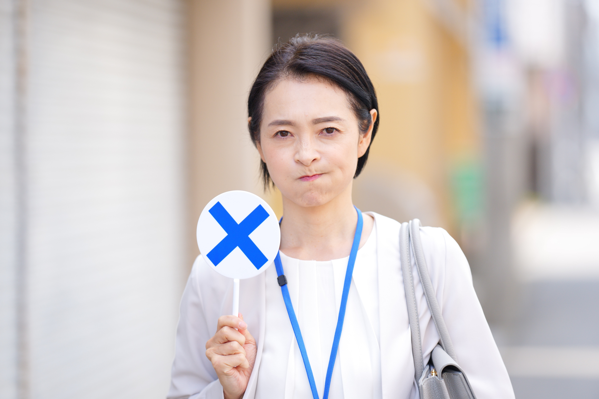 バツの札を持つ女性