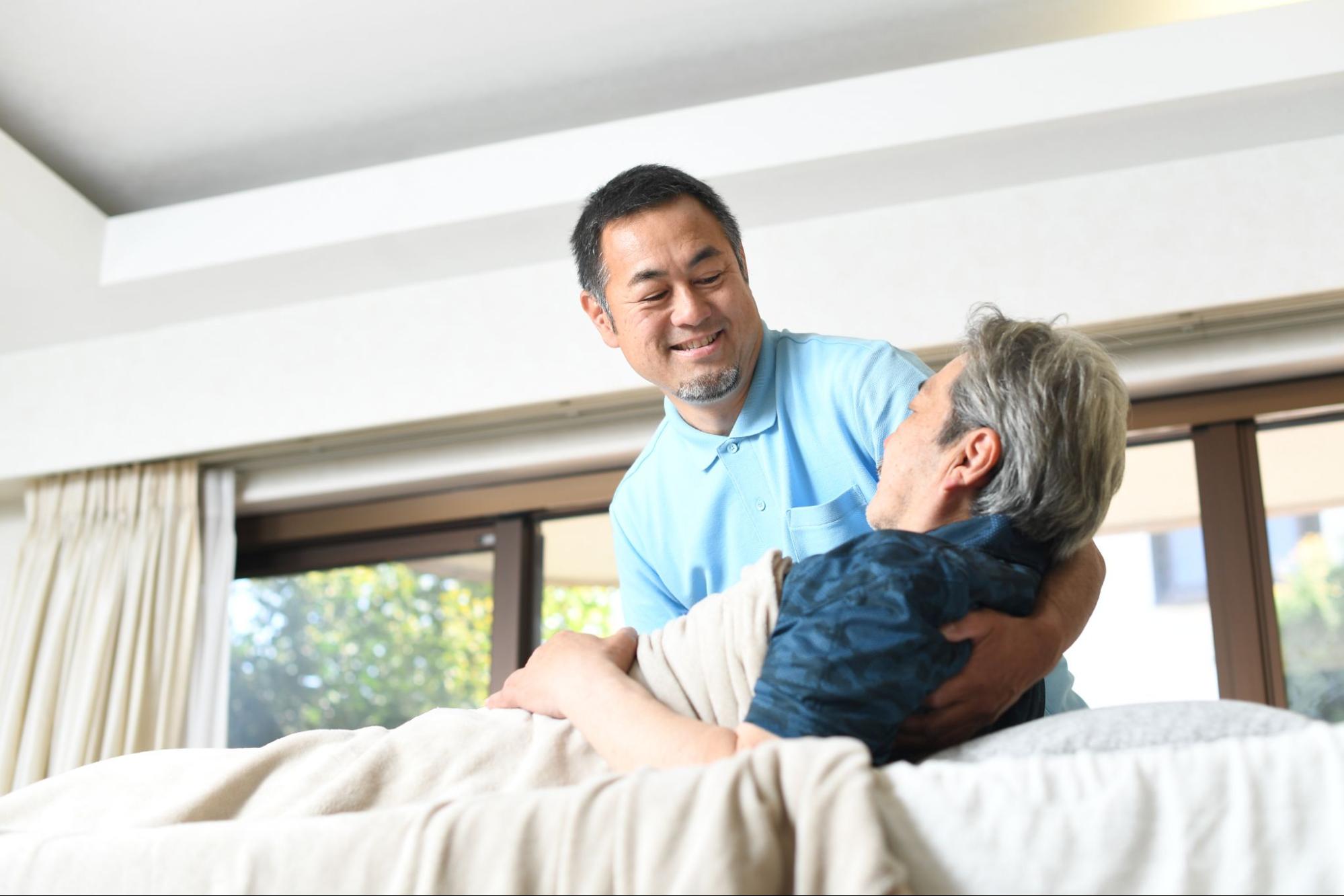 高齢者をベッドで介助する男性介護士
