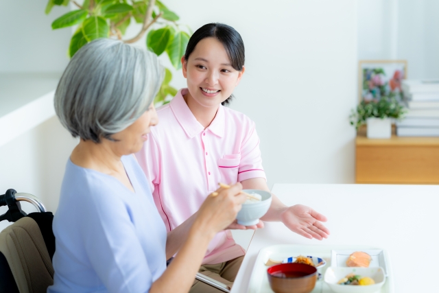 高齢者に食事を出す女性