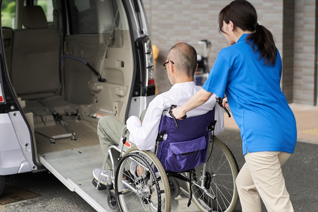 送迎者に車椅子の高齢者を乗せる