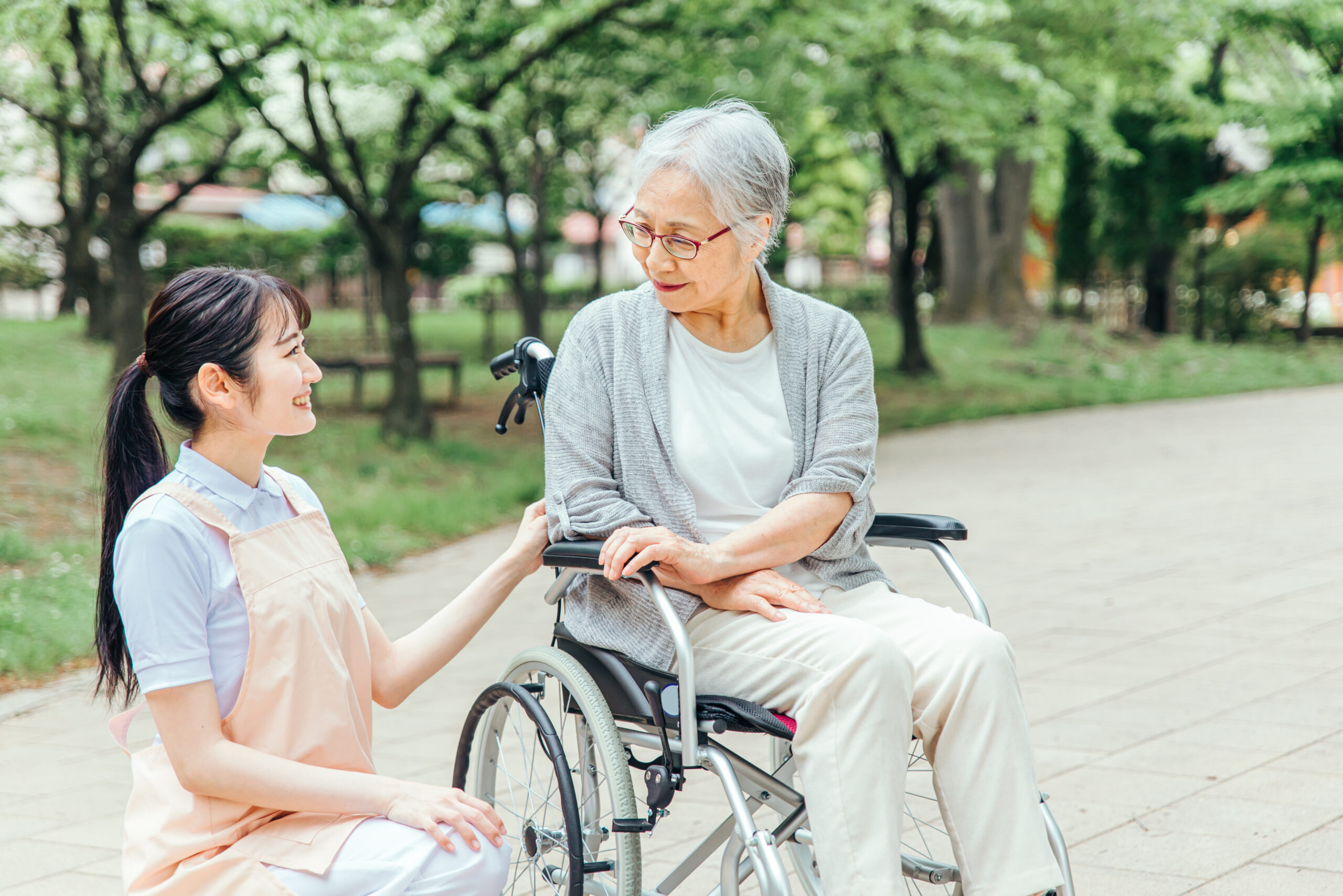 車椅子に乗った高齢者女性と女性スタッフ