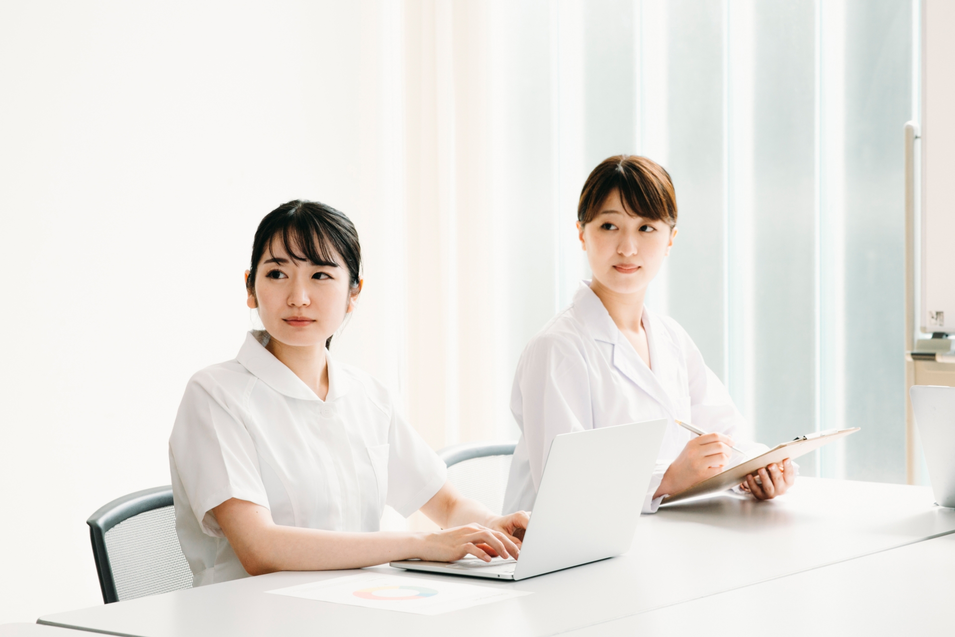 会議する白衣姿の女性（真剣）