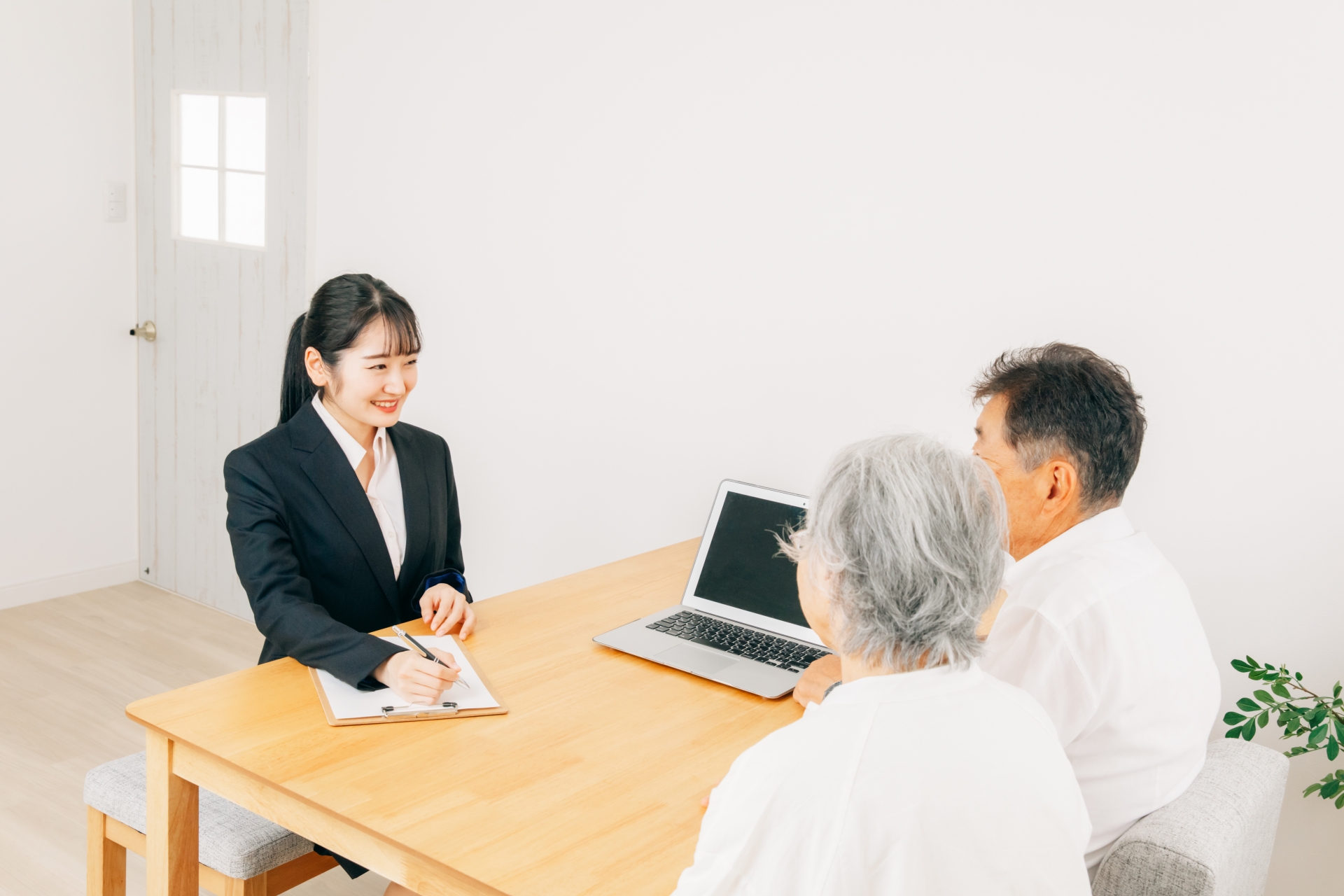 パソコンで説明する女性と高齢者夫婦