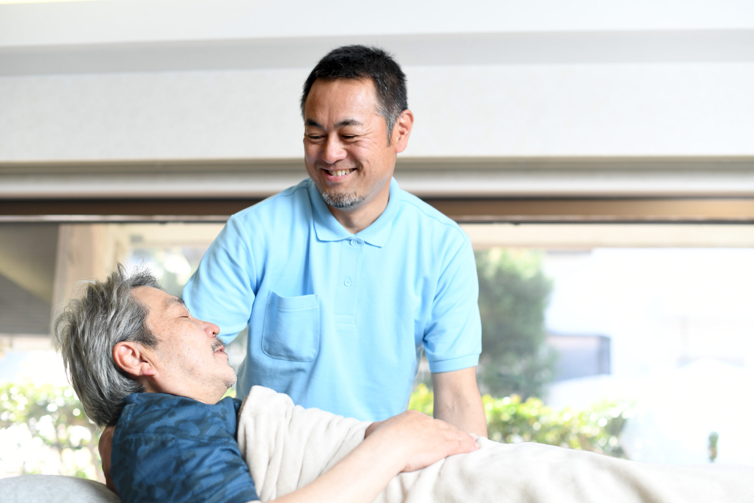 高齢者をベッドで介助する男性介護士