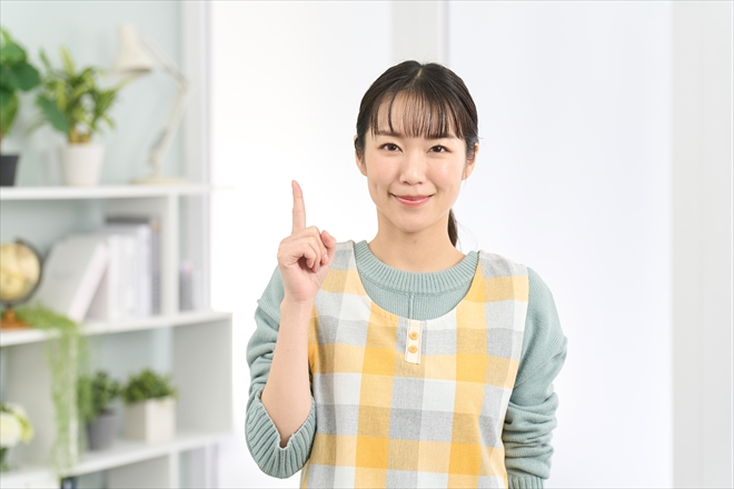 笑顔で指差しをするエプロンを着た女性