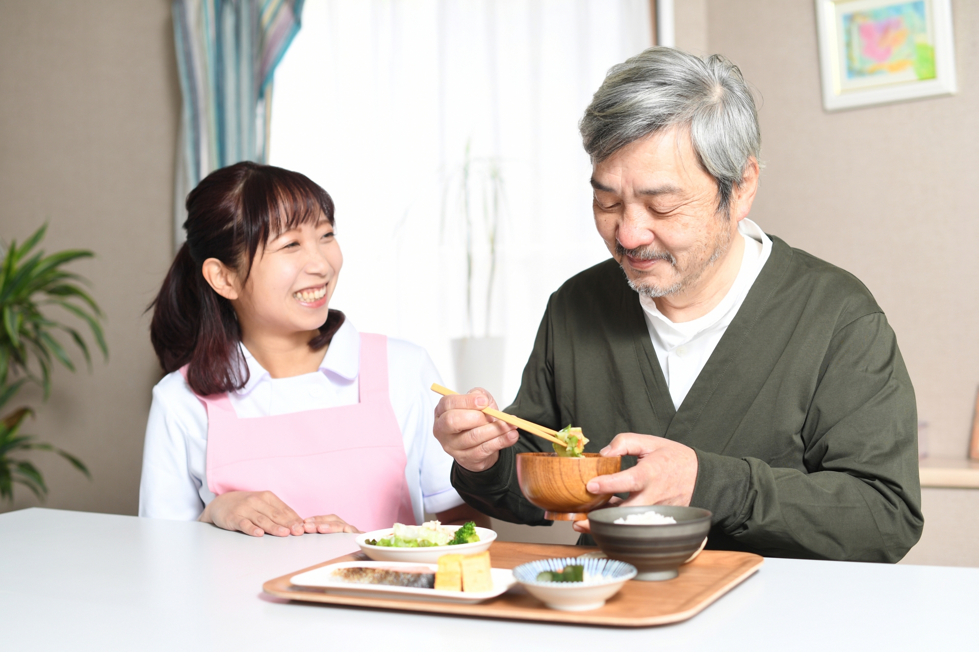 食事をする高齢者男性とエプロン姿の女性介護士