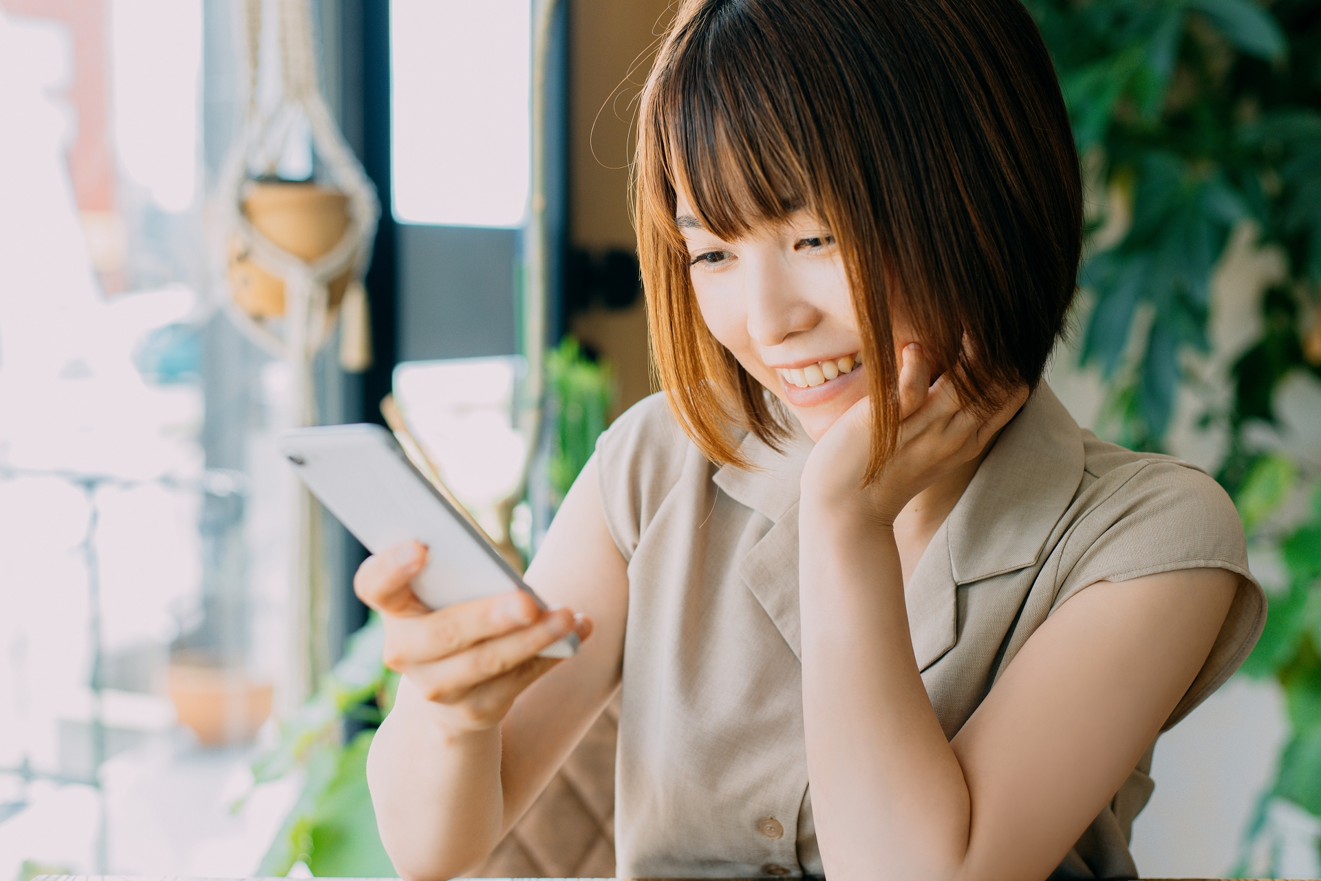 窓際でスマートフォンを使う女性