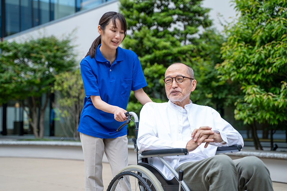 車いすのシニア男性と介護施設スタッフ