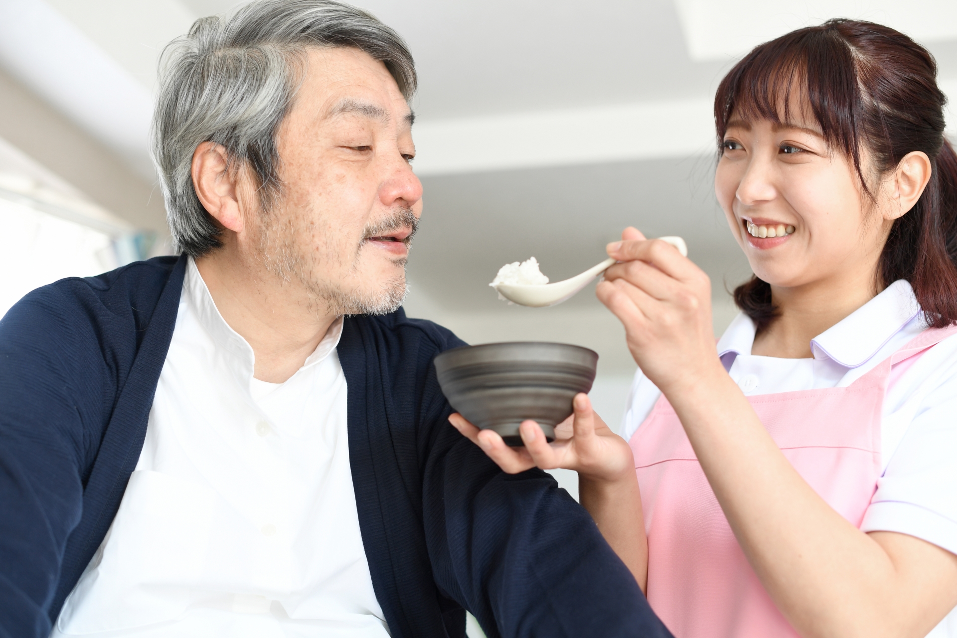 食事介助をする女性介護士と高齢者男性