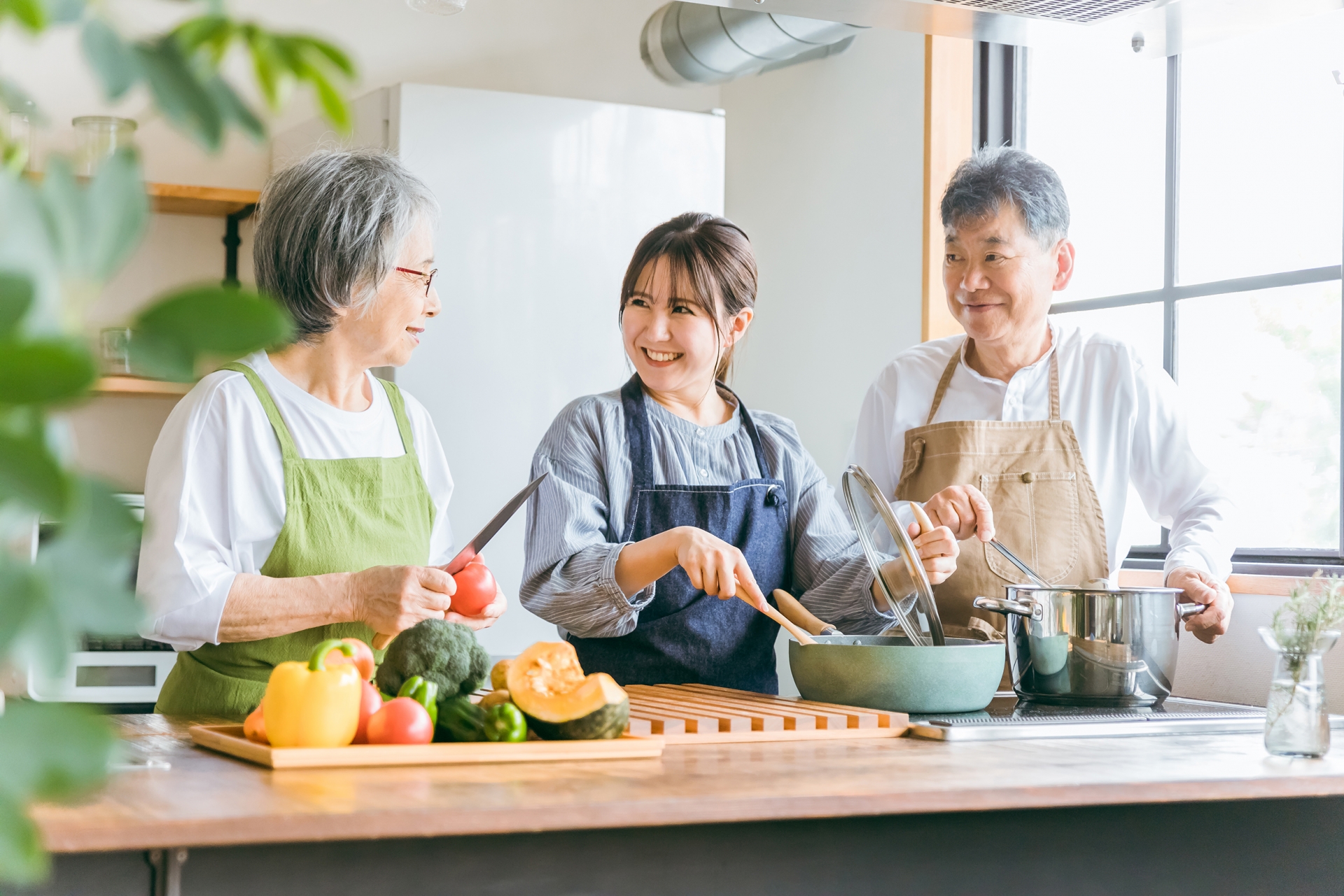 料理する高齢者夫婦と若い女性（料理教室）