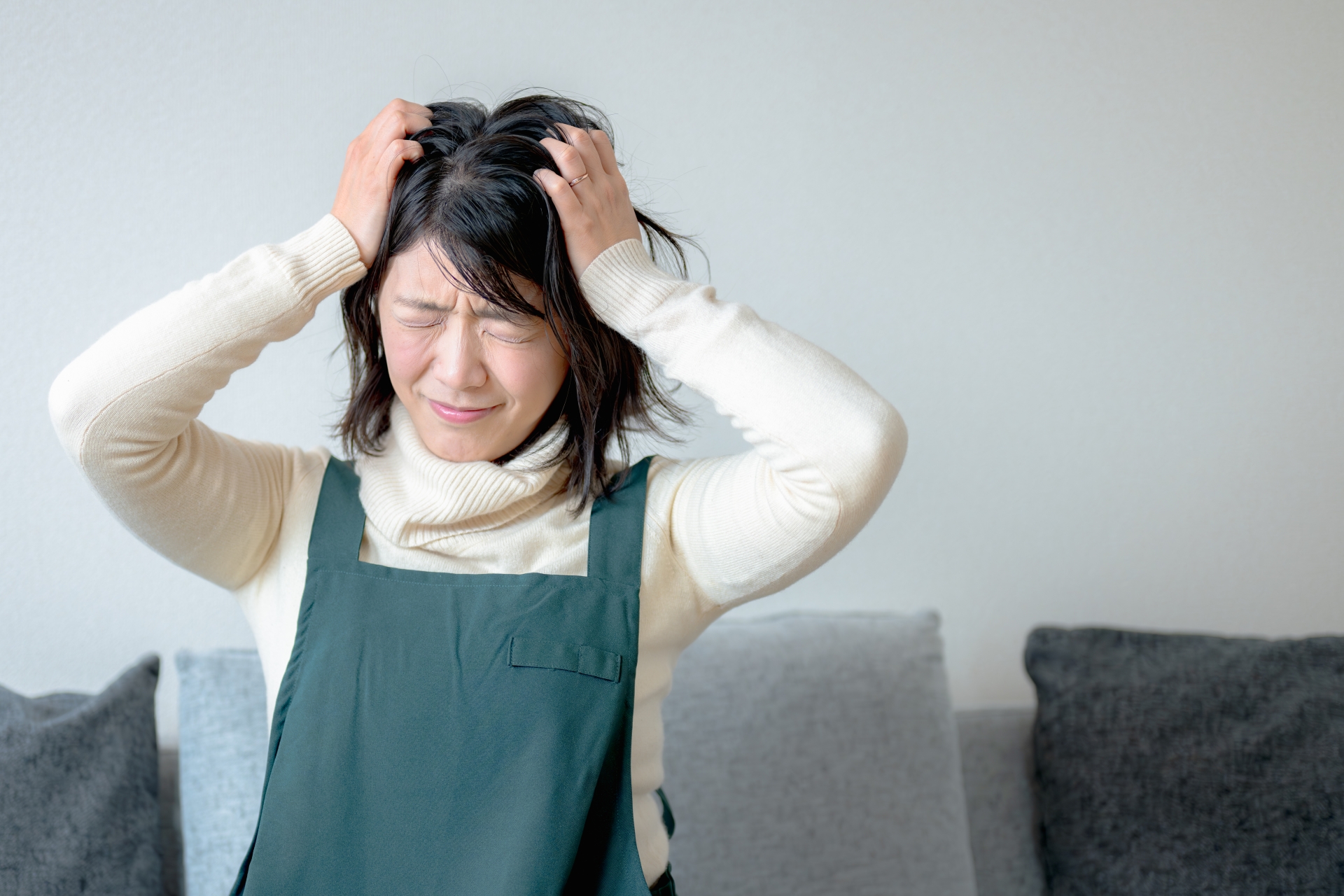頭を抱える若いエプロン女性