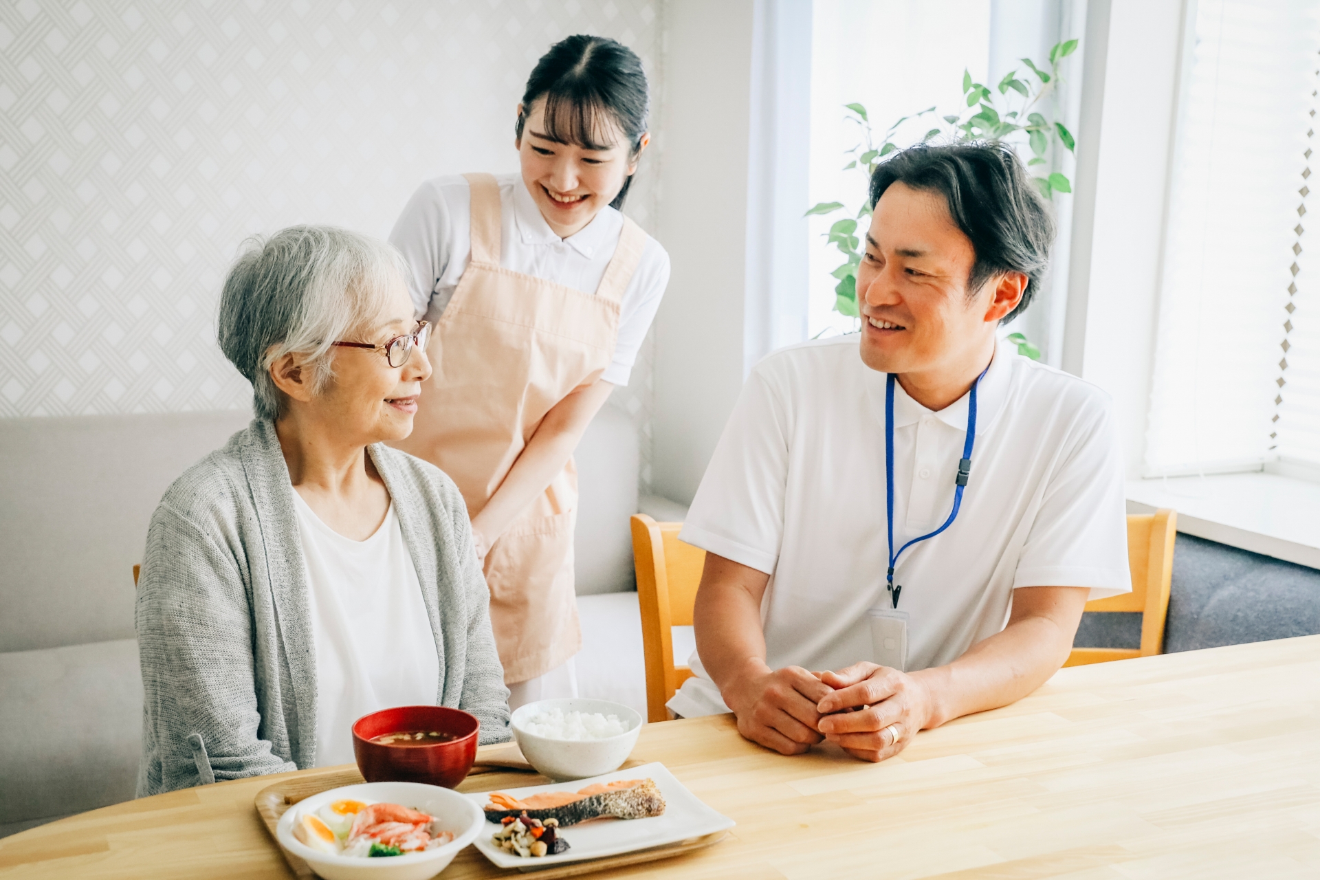 食事する高齢者と男女のスタッフ