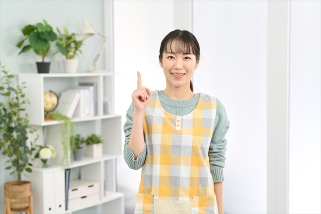 笑顔で指差しをするエプロンを着た女性