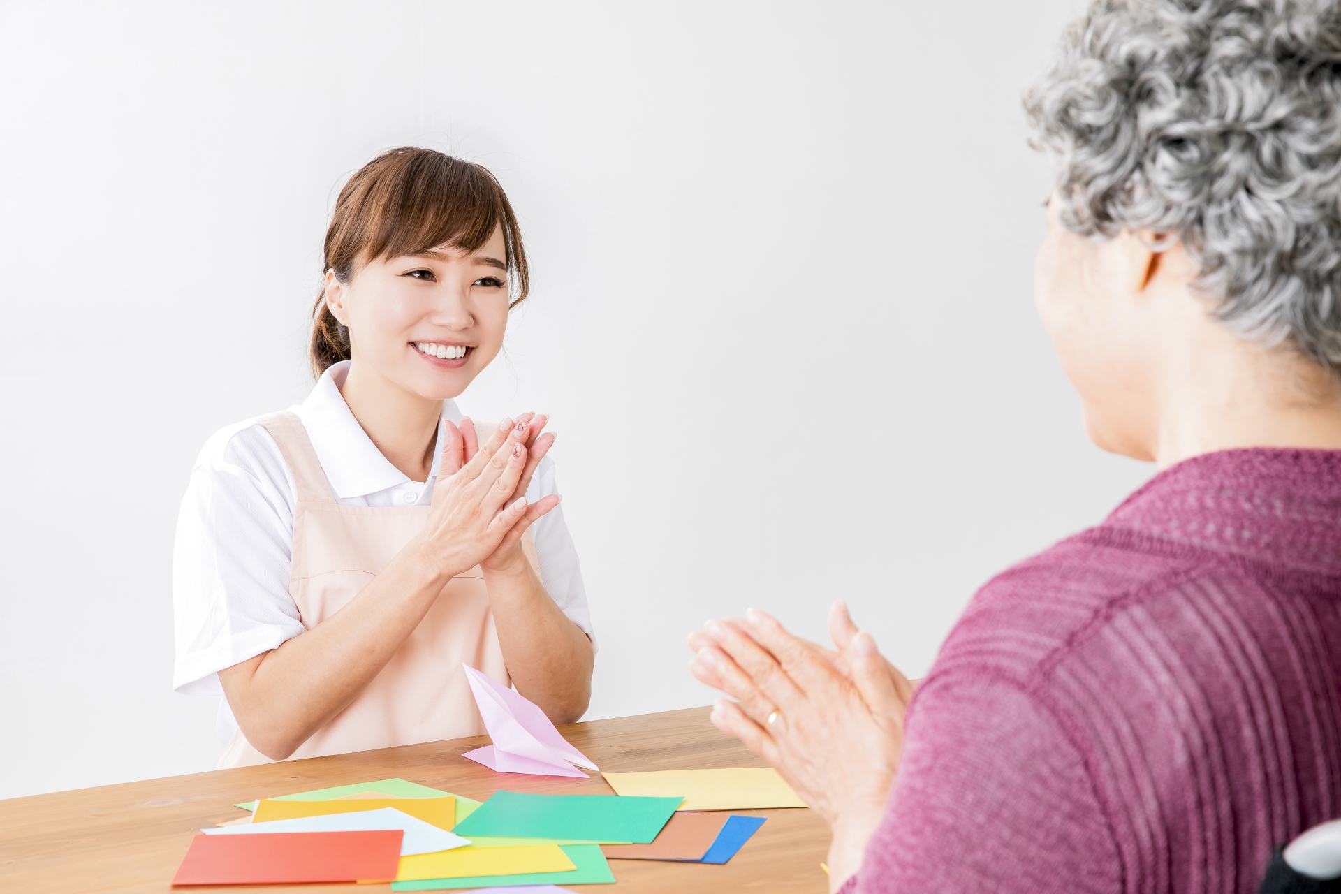 折り紙する高齢者を褒める介護士