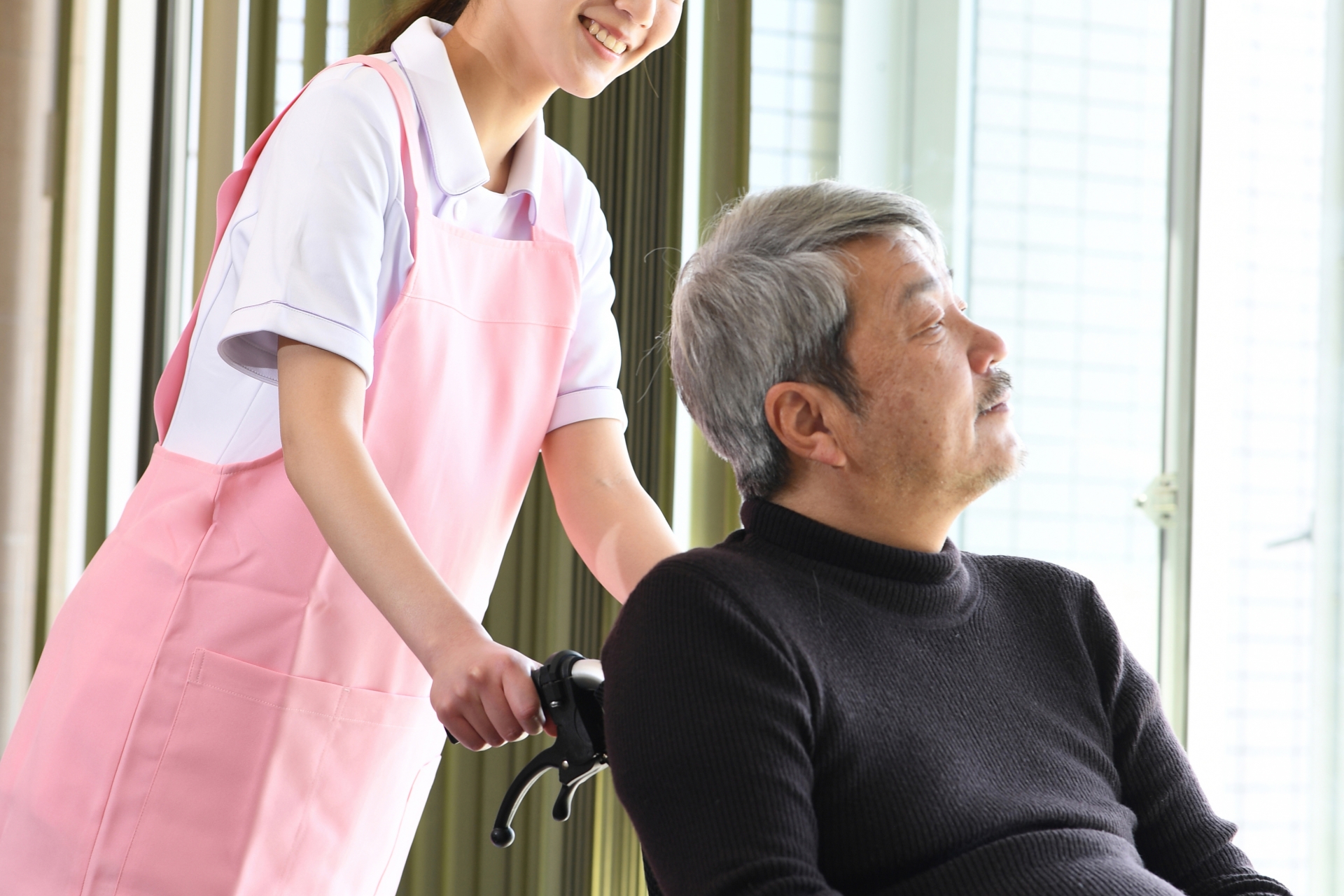 車椅子に乗る高齢者男性と女性の介護士