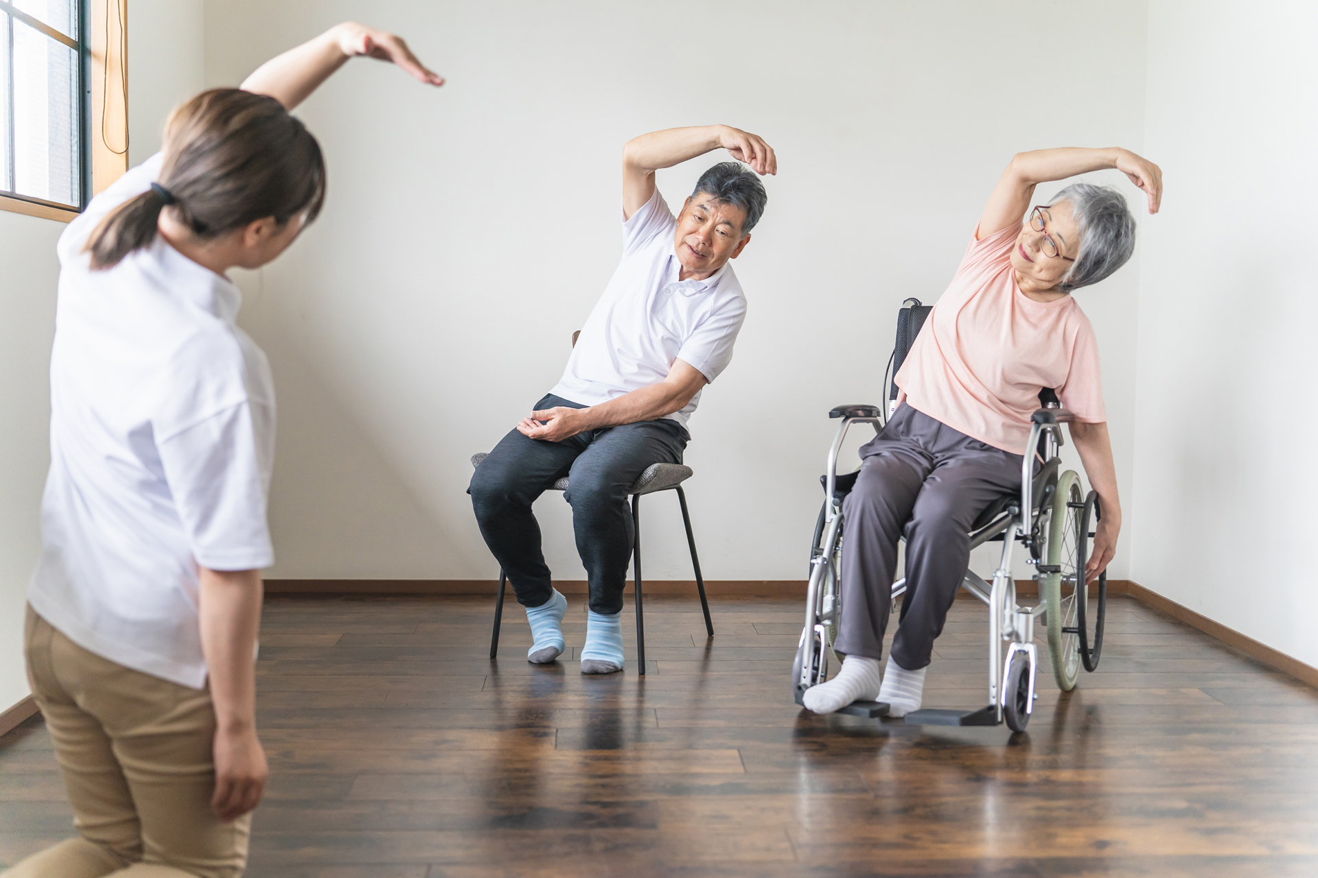 介護施設で体操・運動する高齢者の男女