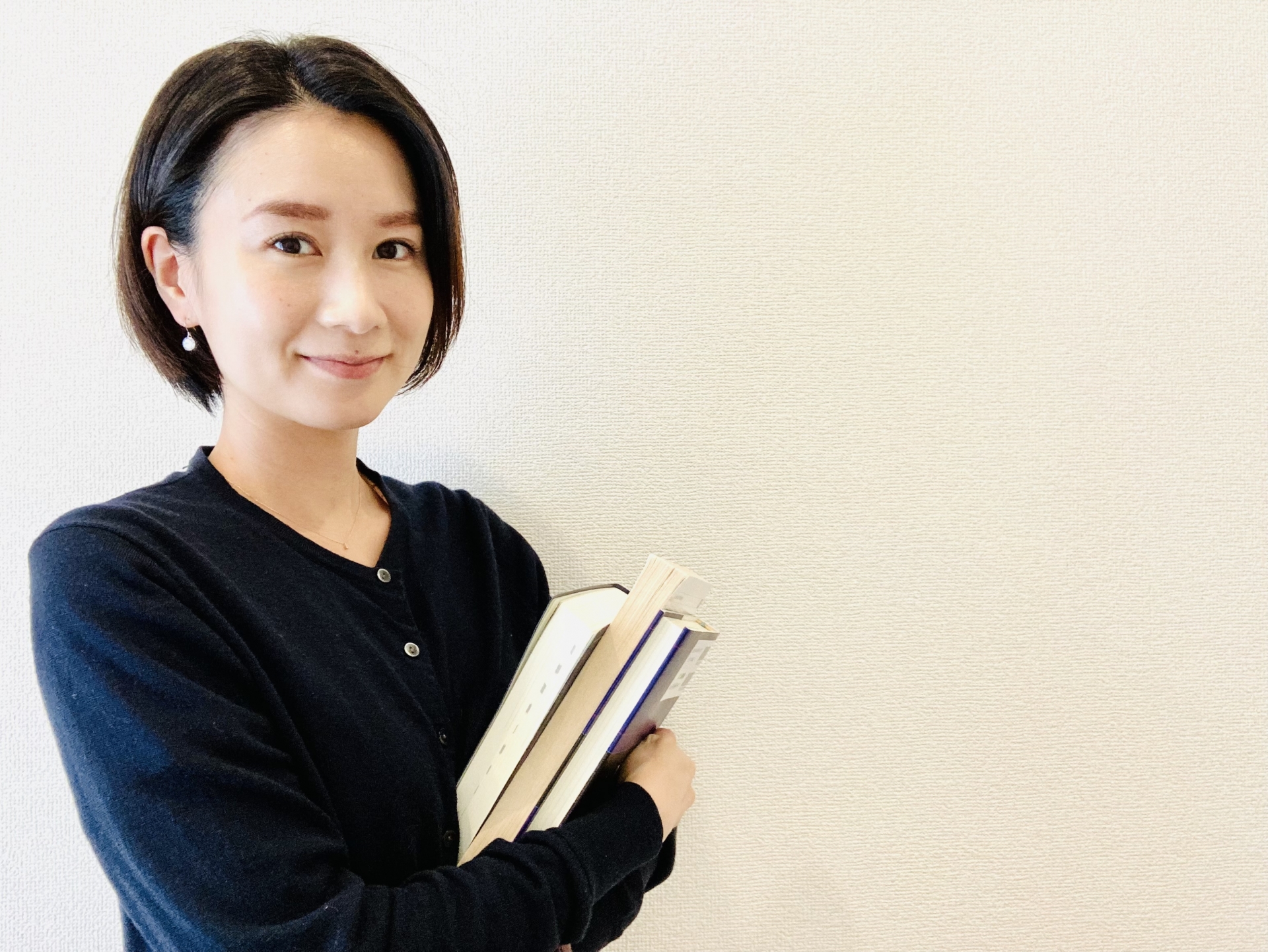 笑顔で本を抱えるショートヘアの女性