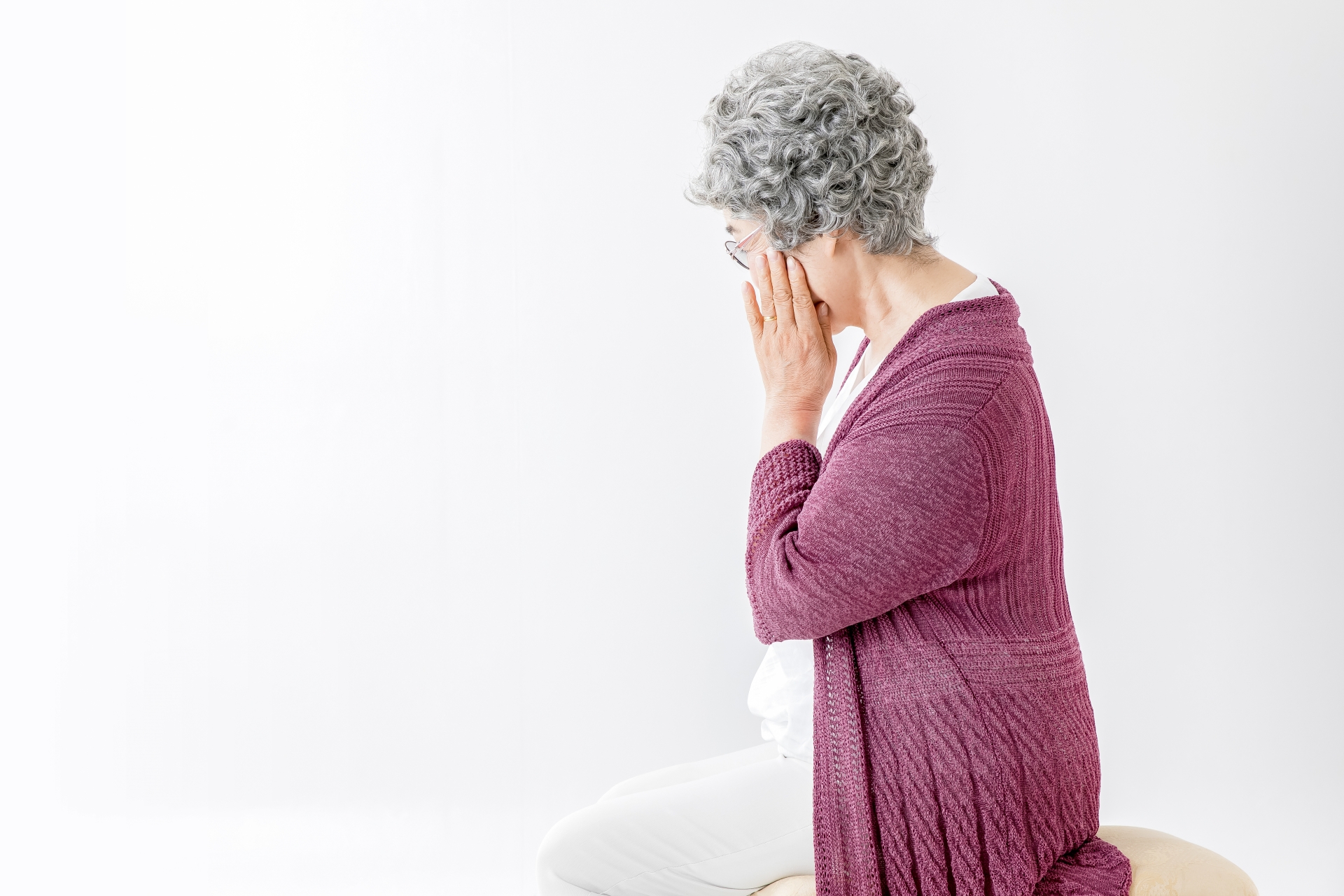 頬を押さえて考える高齢者の女性