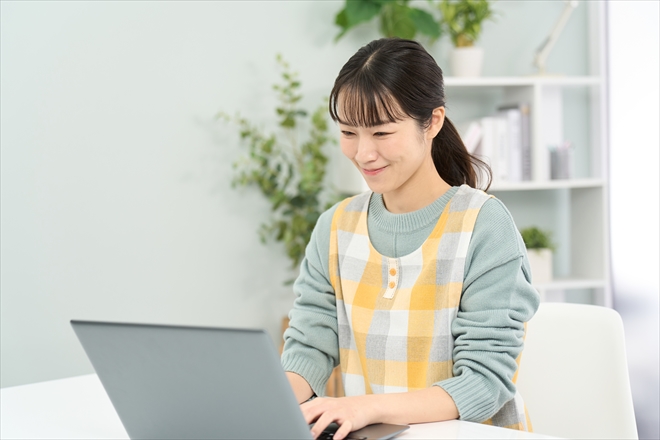 パソコン作業をするエプロンを着た女性