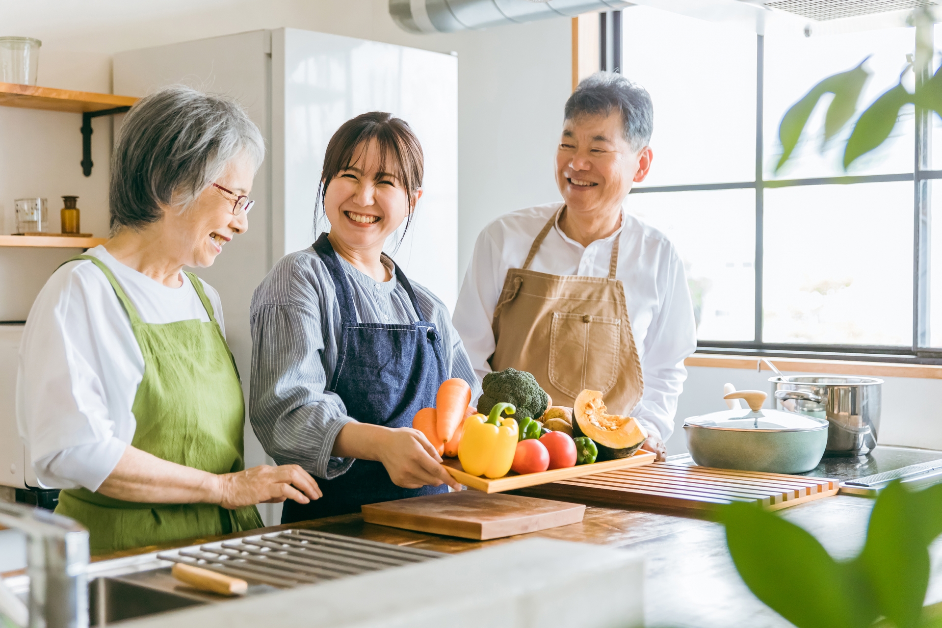 野菜を持つ高齢者夫婦と若い日本人（介護）