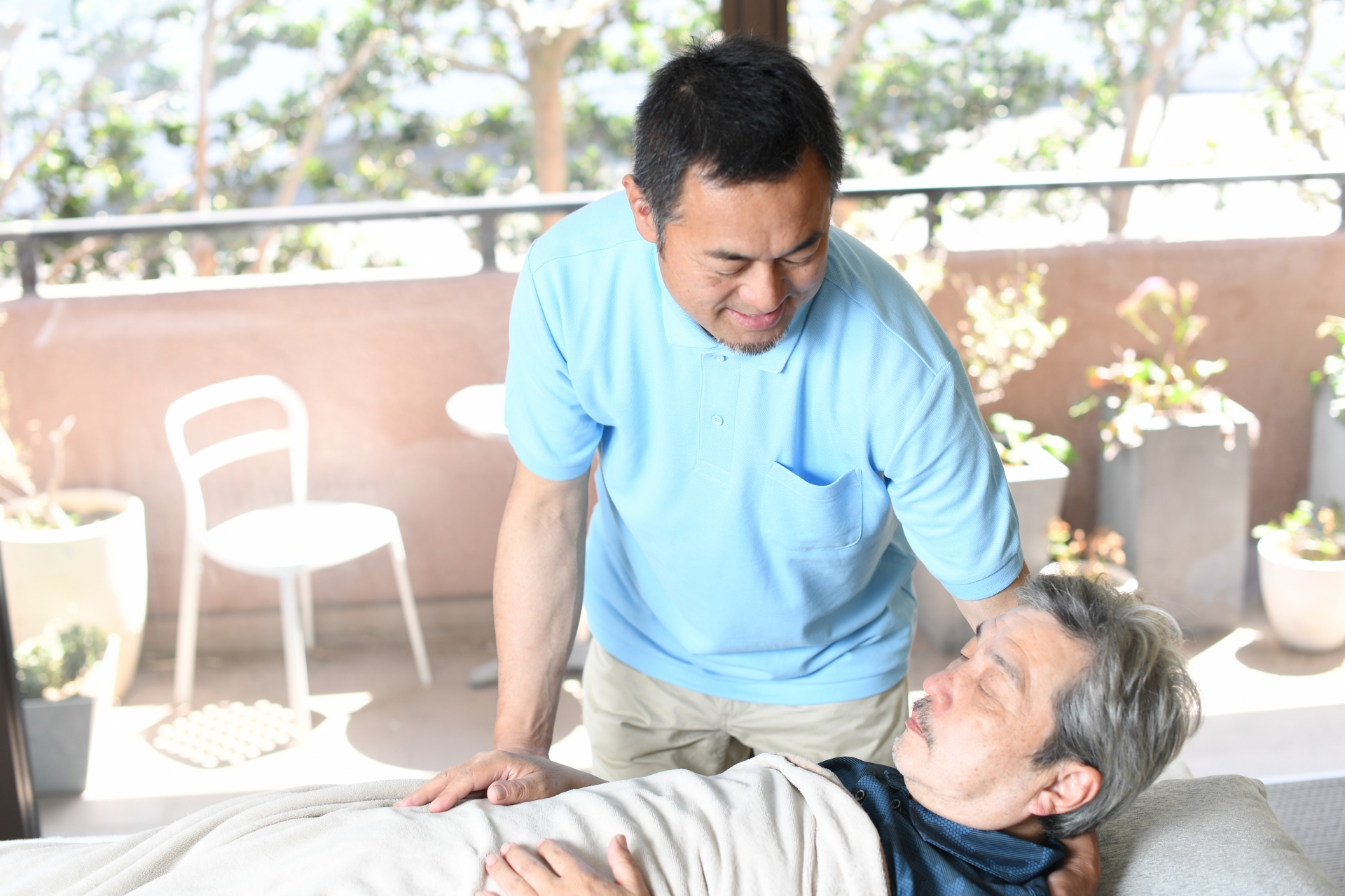 高齢者をベッドで介助する男性介護士