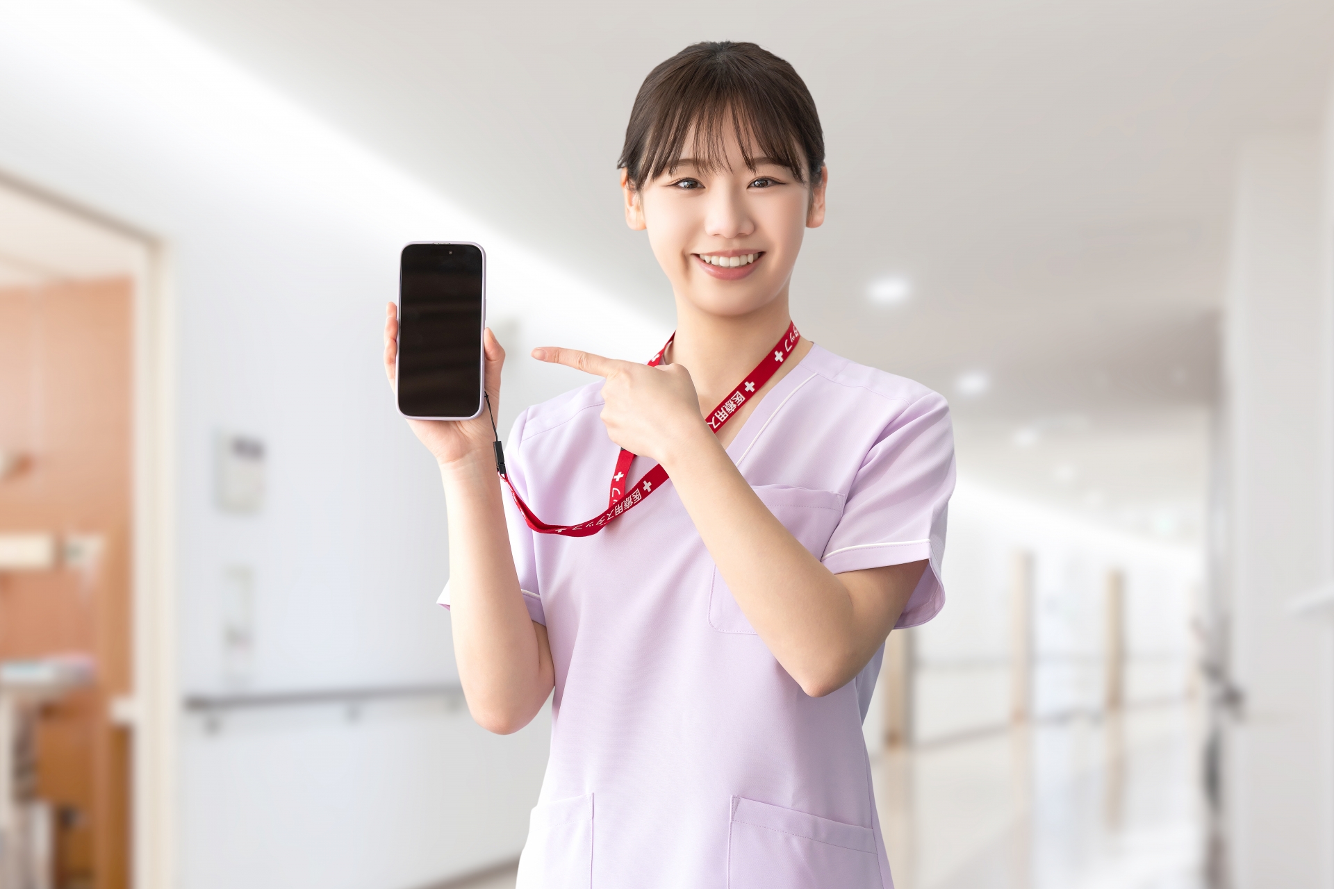 スマホを指差す笑顔の女性医療スタッフ
