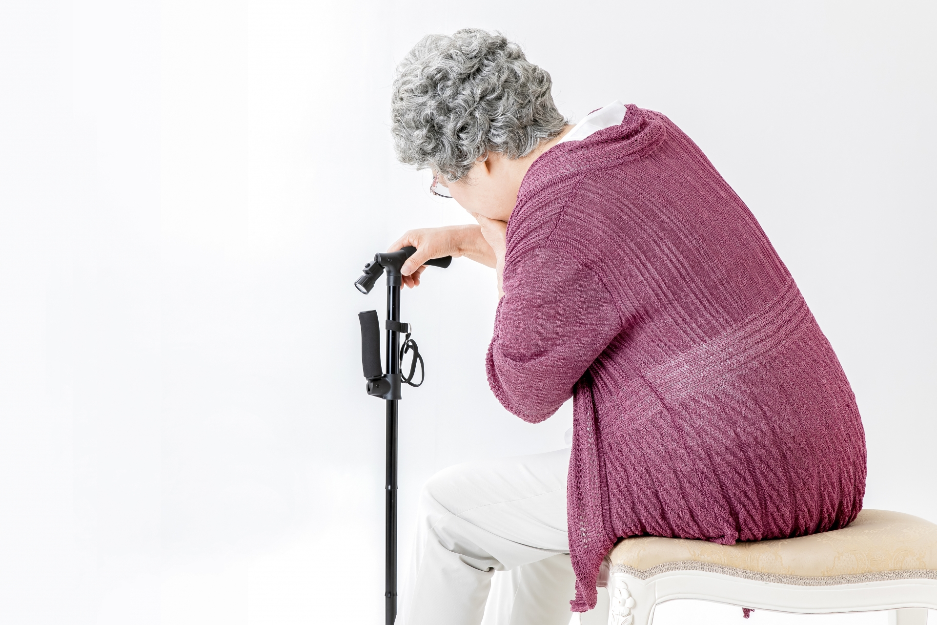 杖をついて苦しむ高齢者の女性