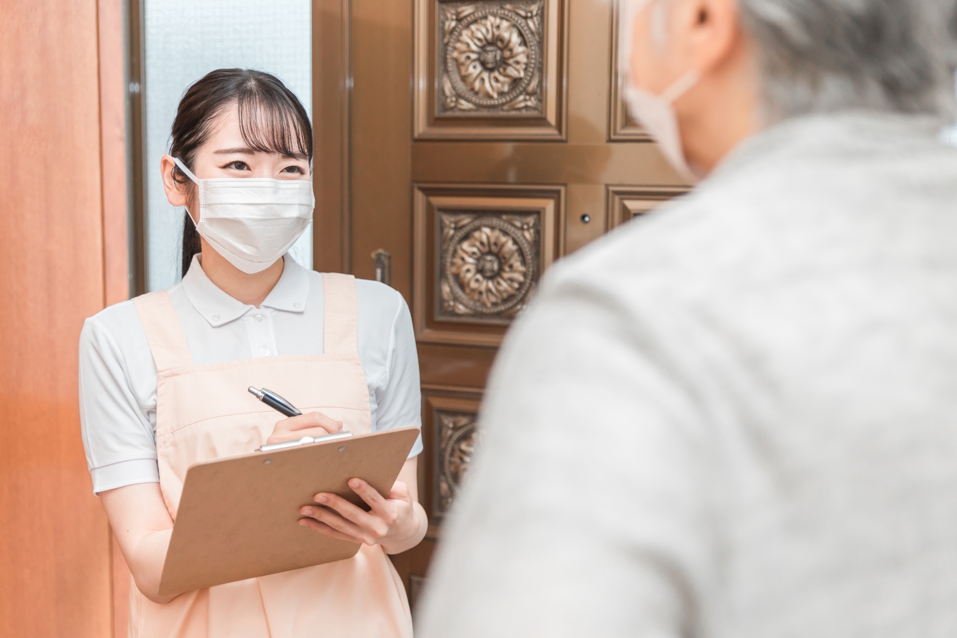 高齢者住宅に訪問する女性（書類・マスク）