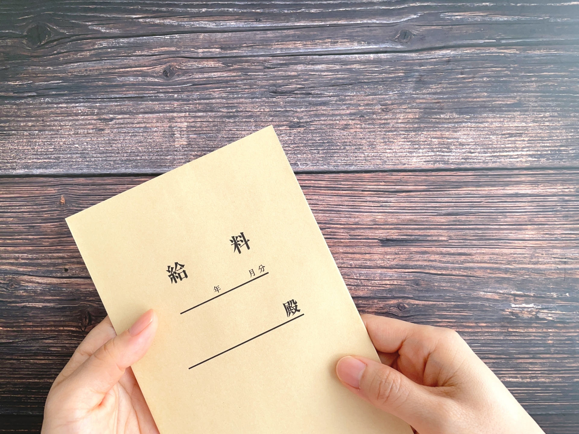 机上で給料袋を持つ女性の手元