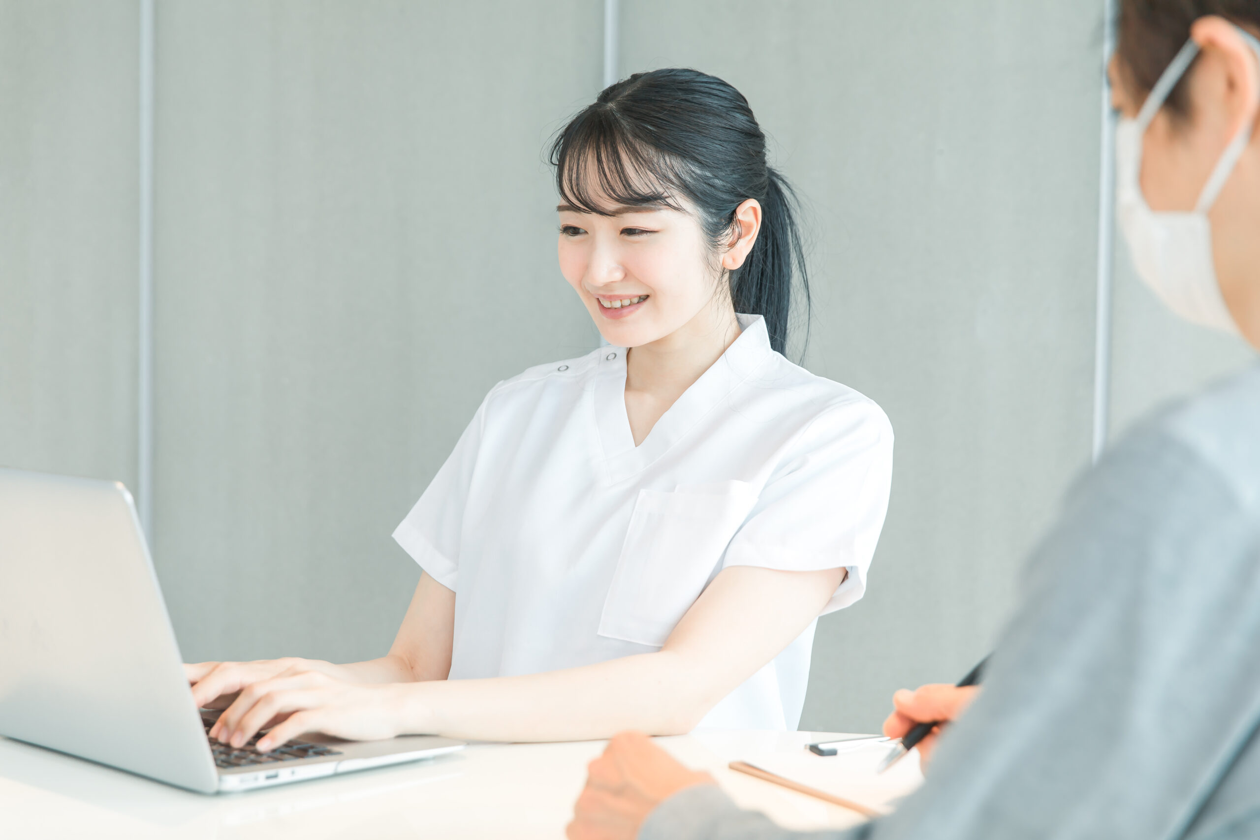 ソコンで受付する白衣の女性と患者