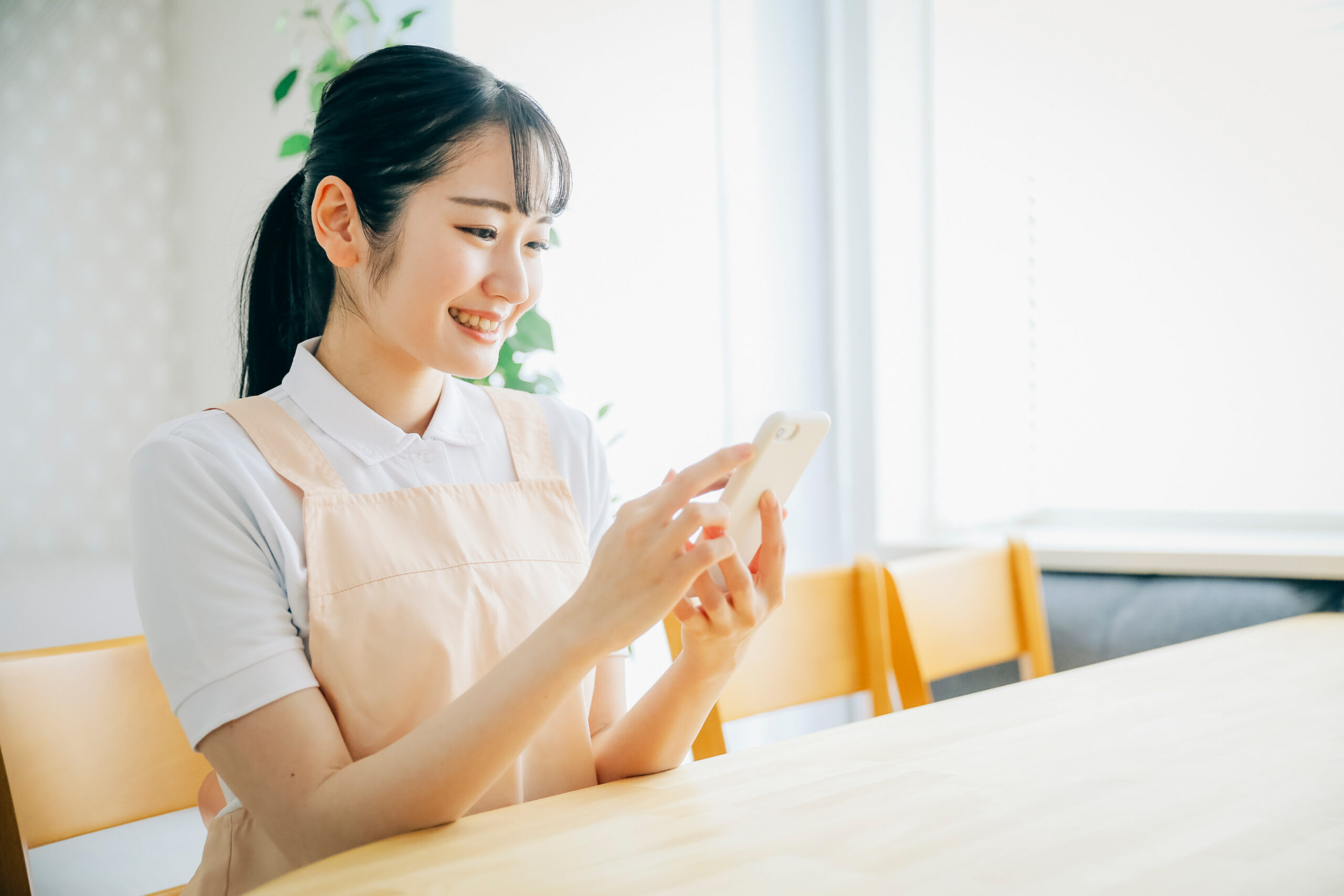 スマホを使うエプロン姿の女性
