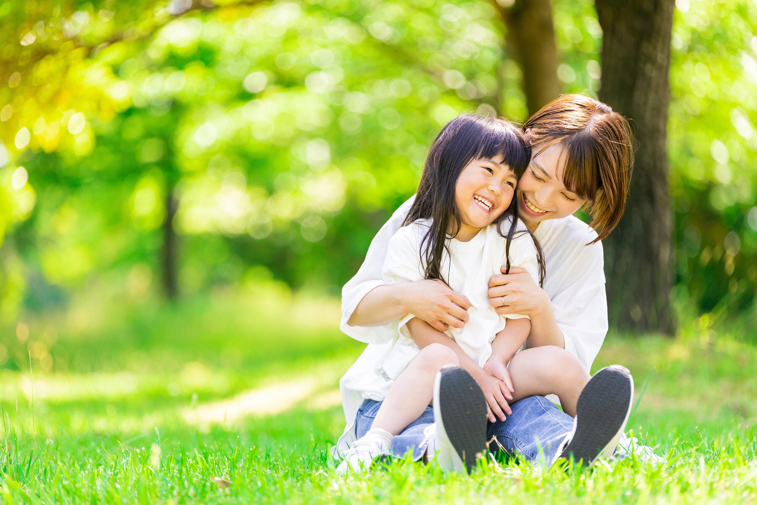 新緑の中で女の子を抱く笑顔の母親