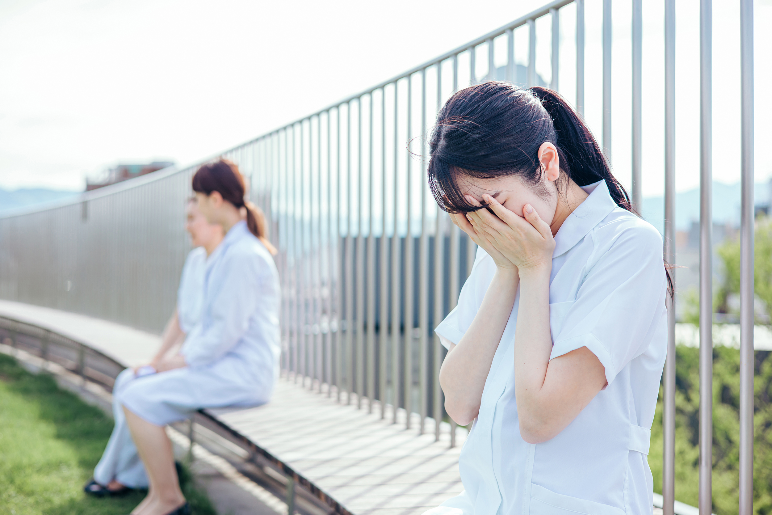 病院の屋上で泣く女性看護師