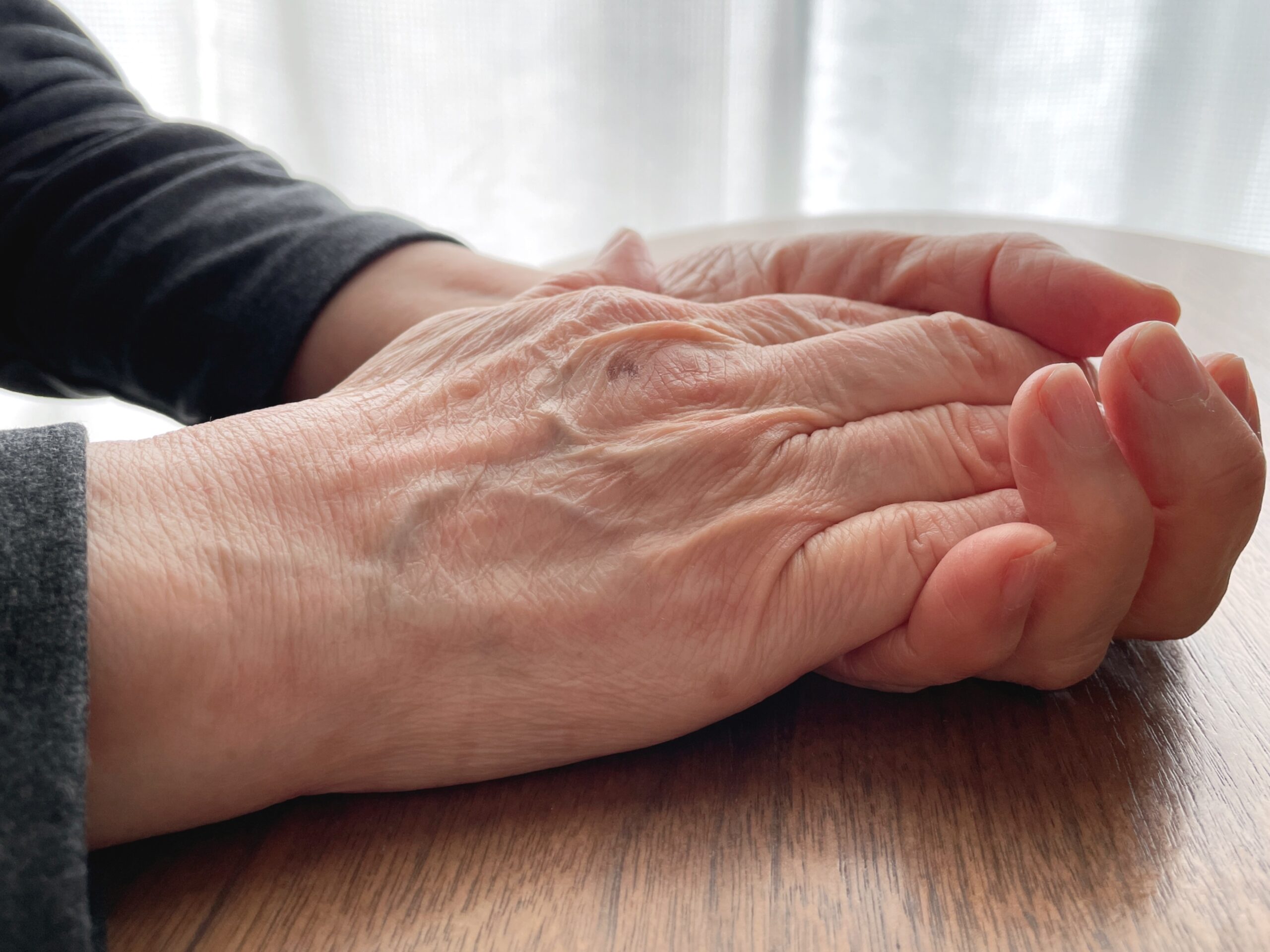 机上で手を重ねる高齢女性