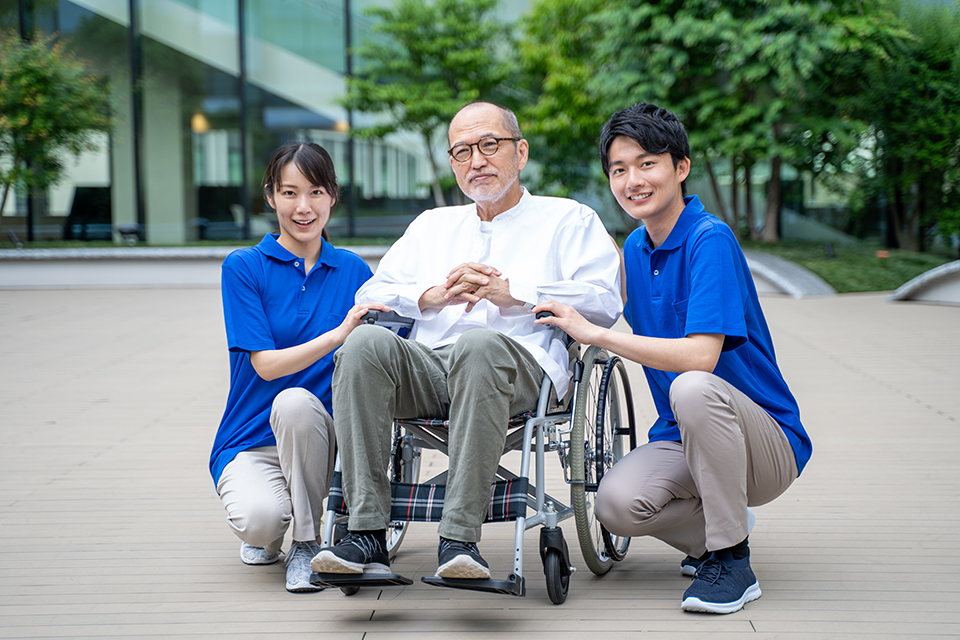 車いすのシニア男性と介護施設スタッフ