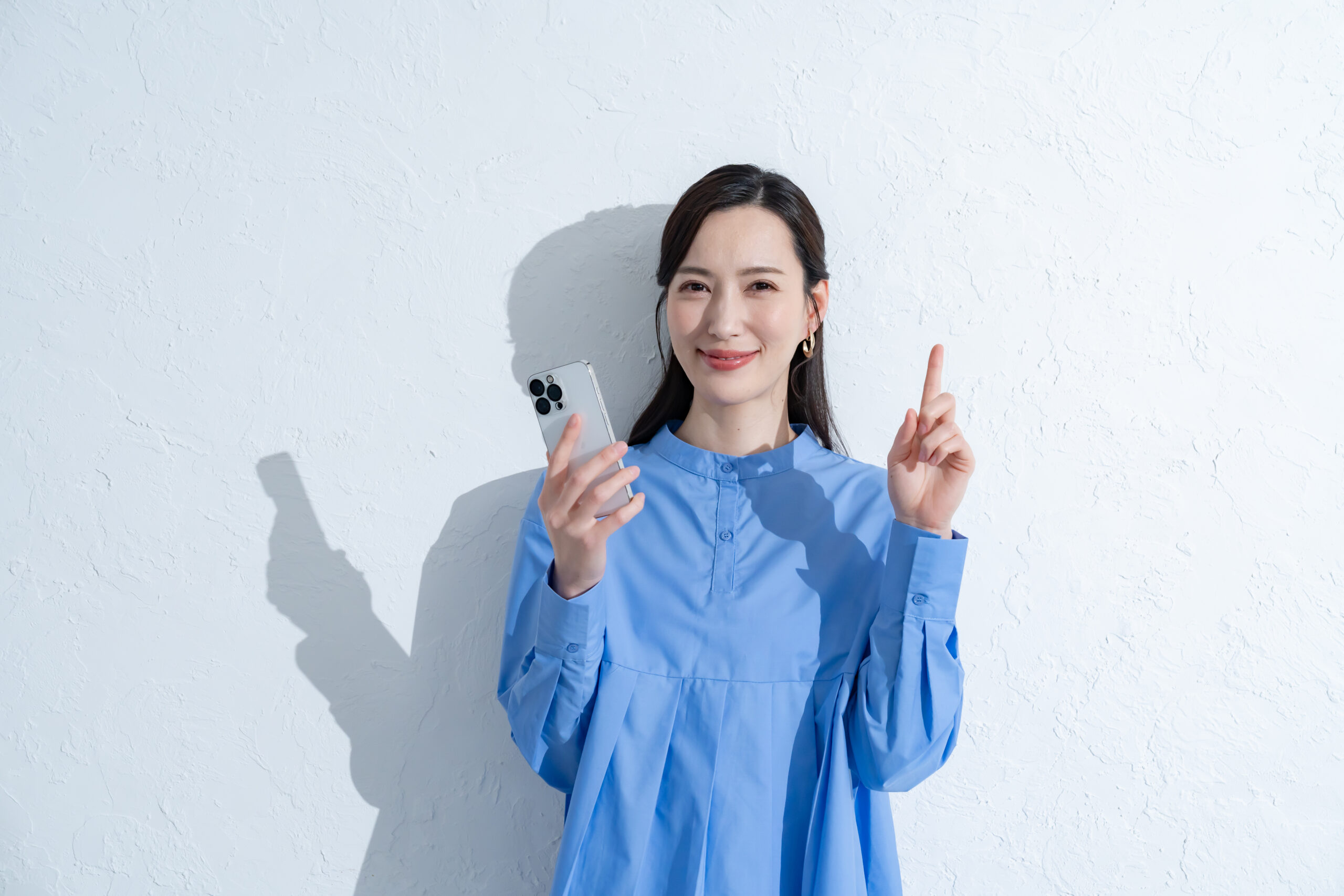 携帯を持つ青いワンピースを着た女性