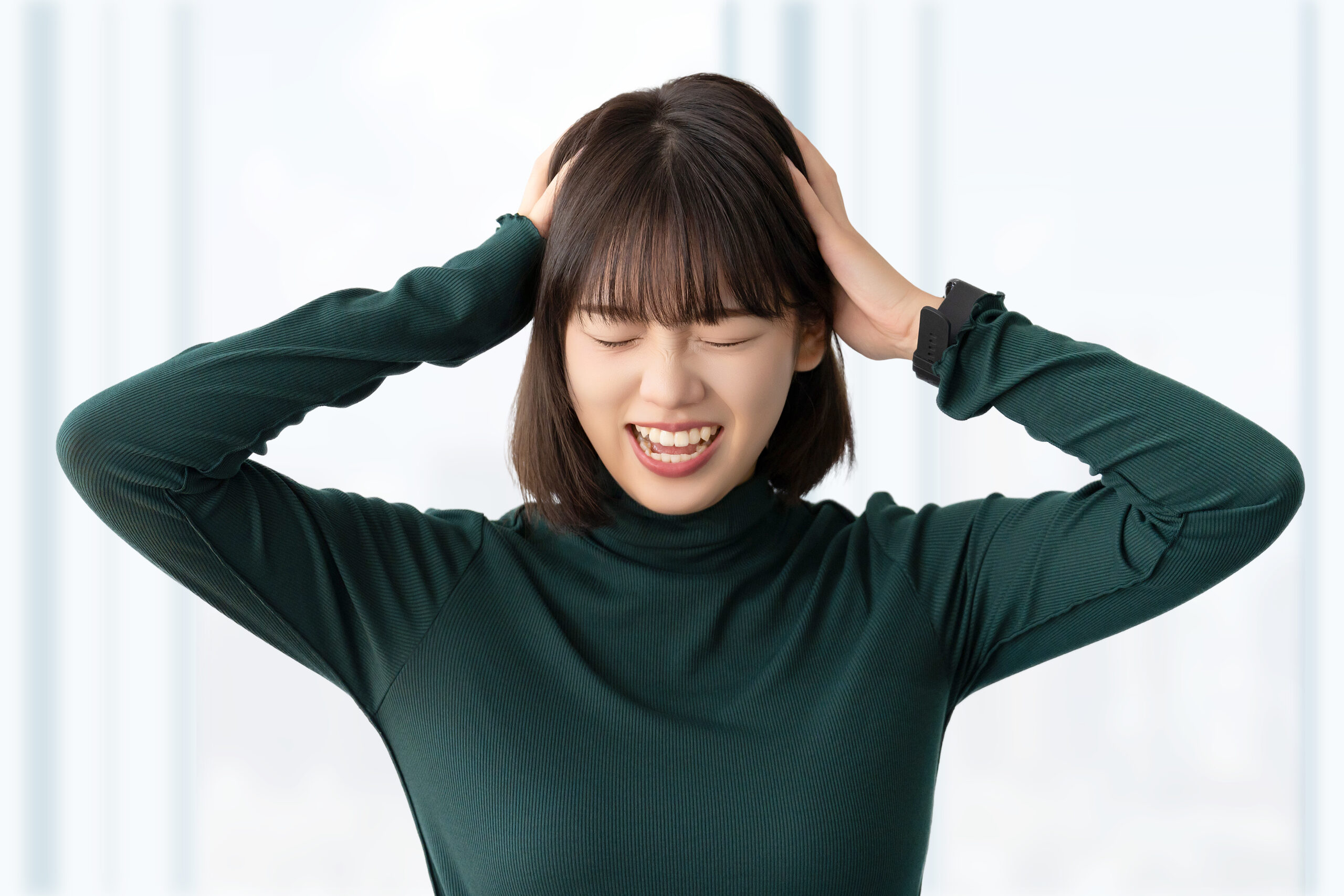 頭を抱えて困る若い女性・ビジネスウーマン