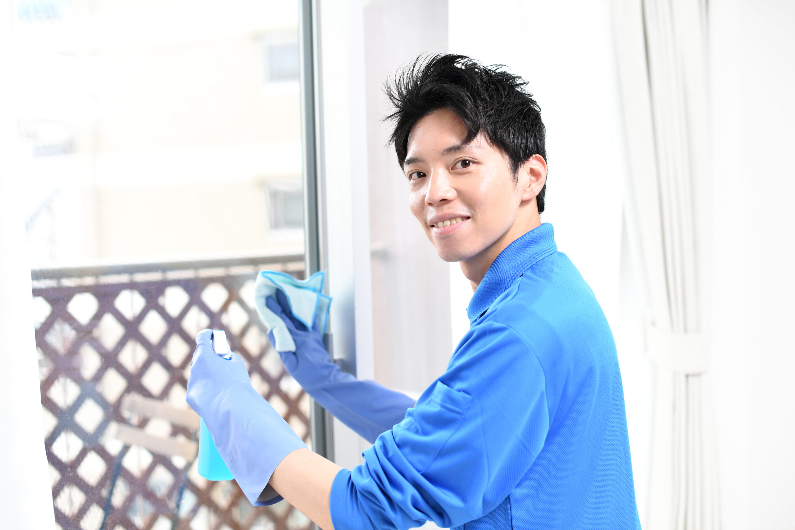 窓拭きをする清掃業のの作業服の若い男性