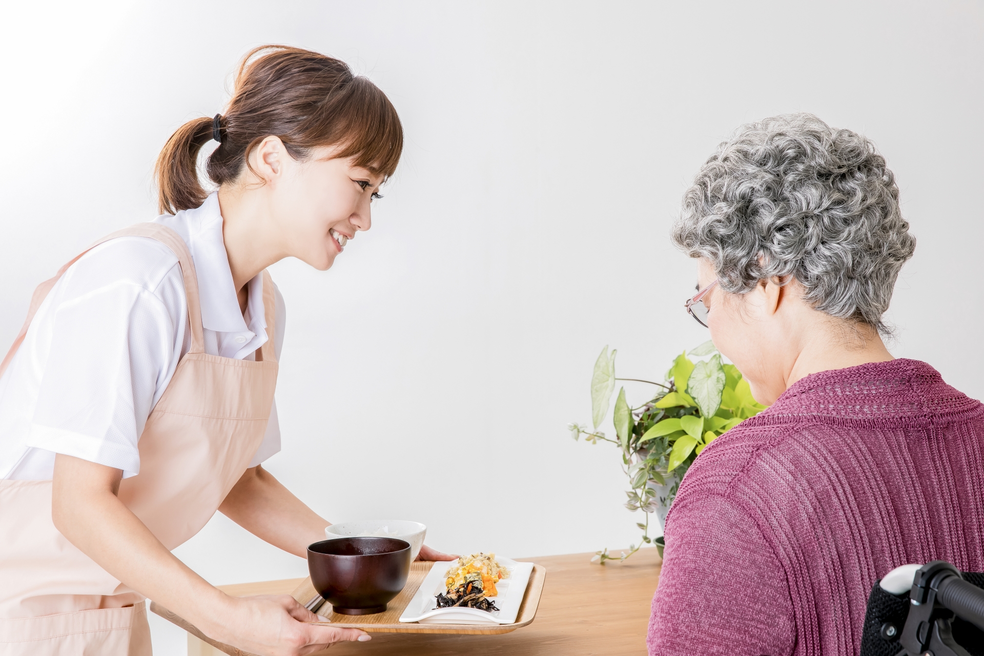 高齢者の女性と食事を運ぶ介護士