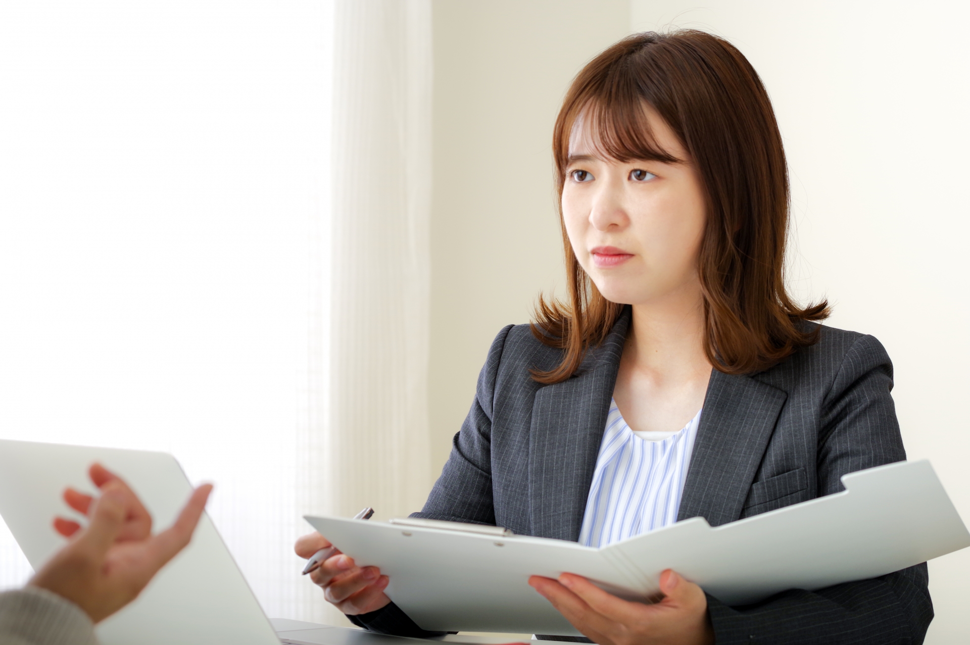 真剣な表情で話を聞くスーツの女性