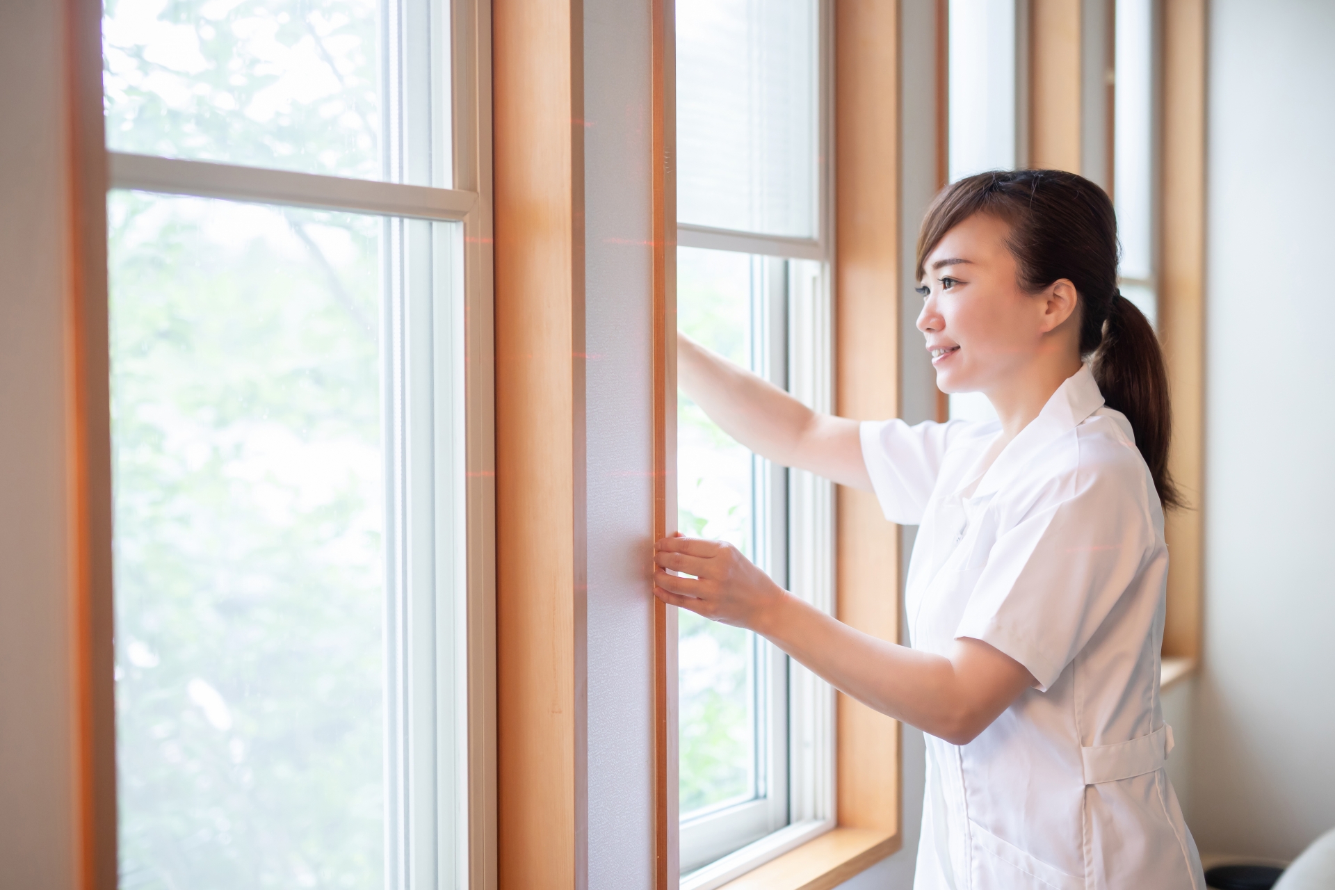 窓を開ける白衣の女性