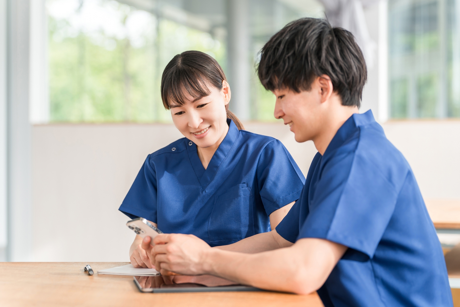 スマホを見ながら会話する先輩と若い看護師