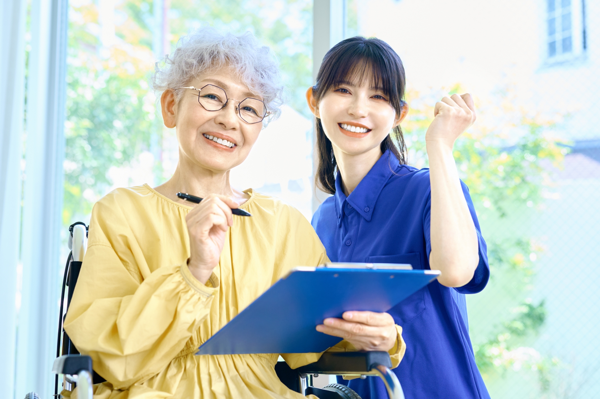 ガッツポーズの車椅子の女性と介護士