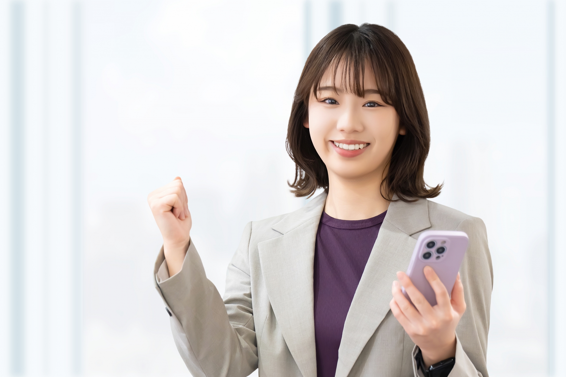 スマホを持ってガッツポーズをする若い女性