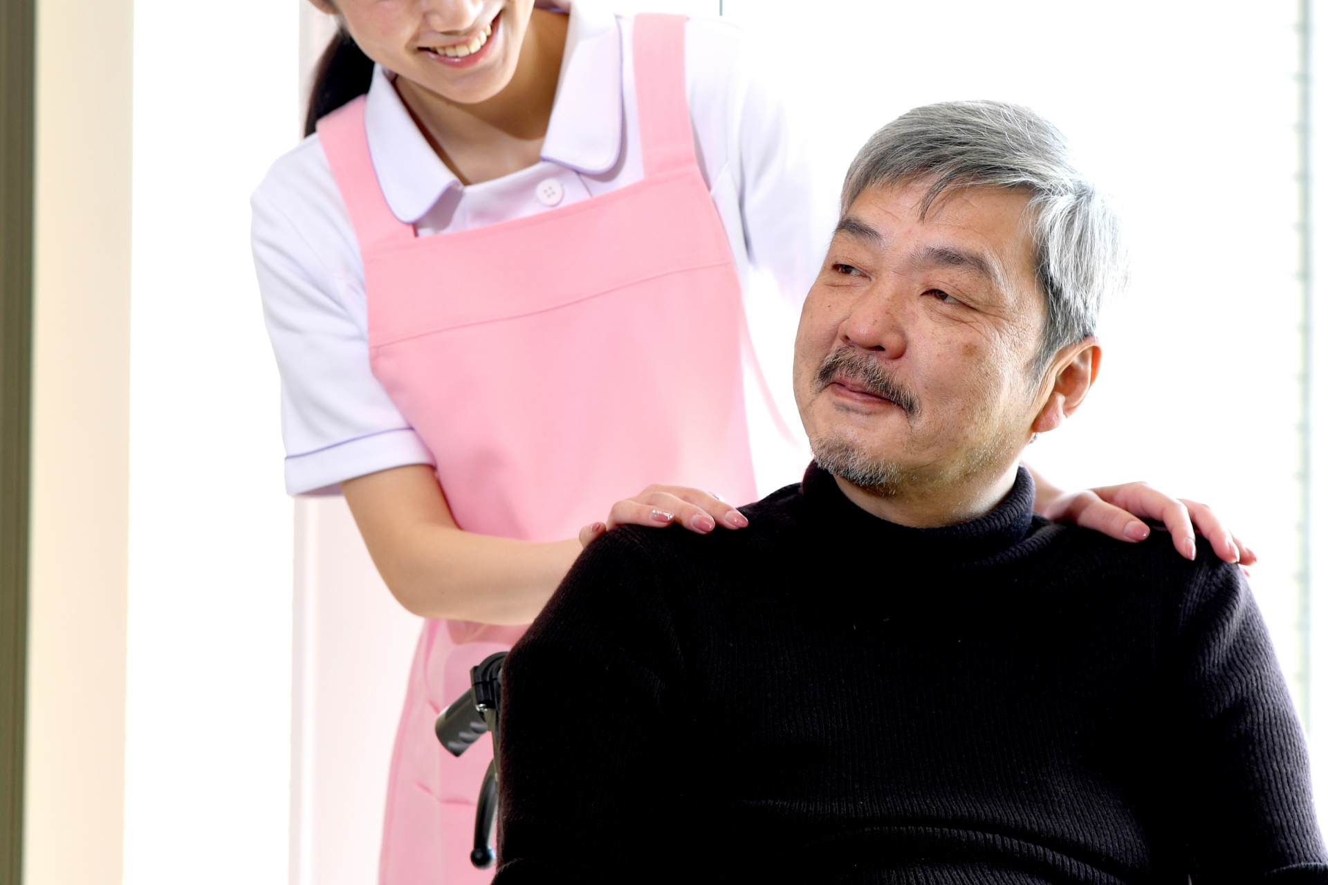 男性利用者の肩に手を置く介護士