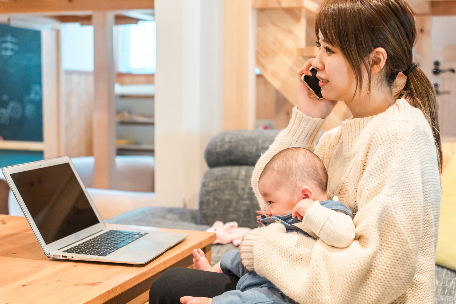 赤ん坊を世話しながら仕事する女性