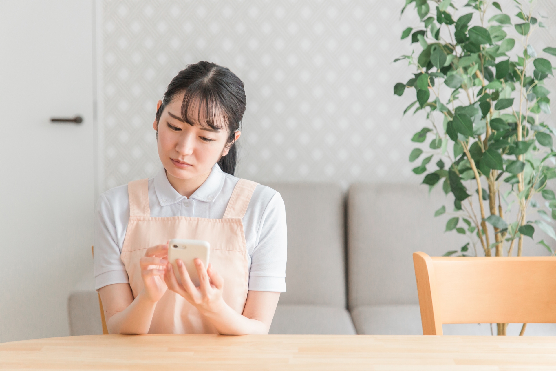 スマホを使うエプロン姿の女性